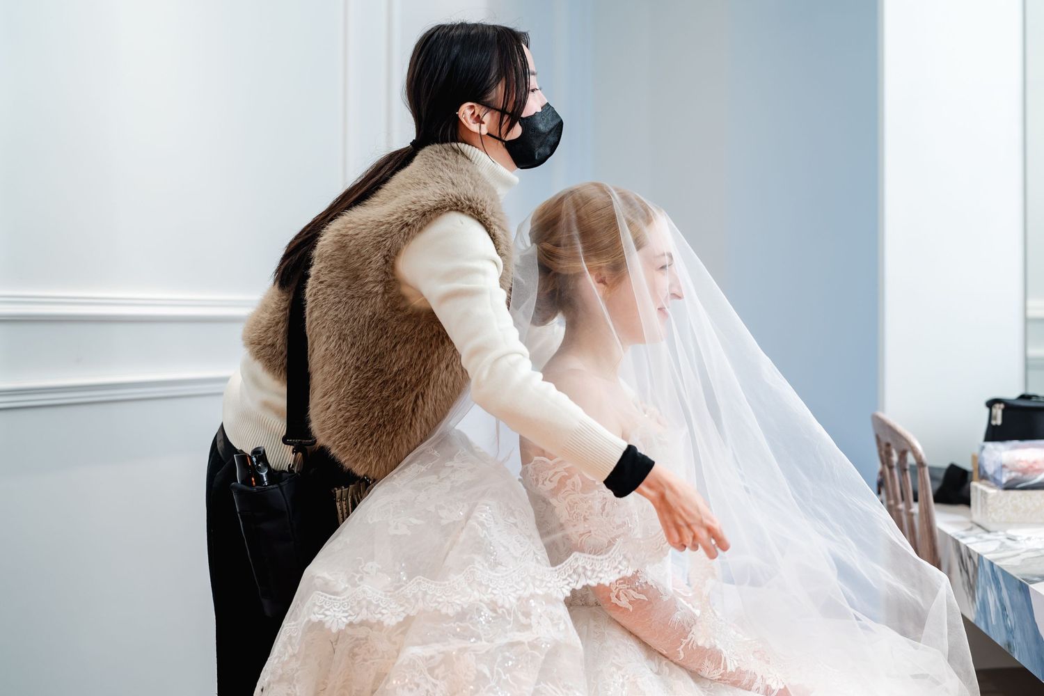 Wedding dress fitting scene with stylish lace details and flowing veil.