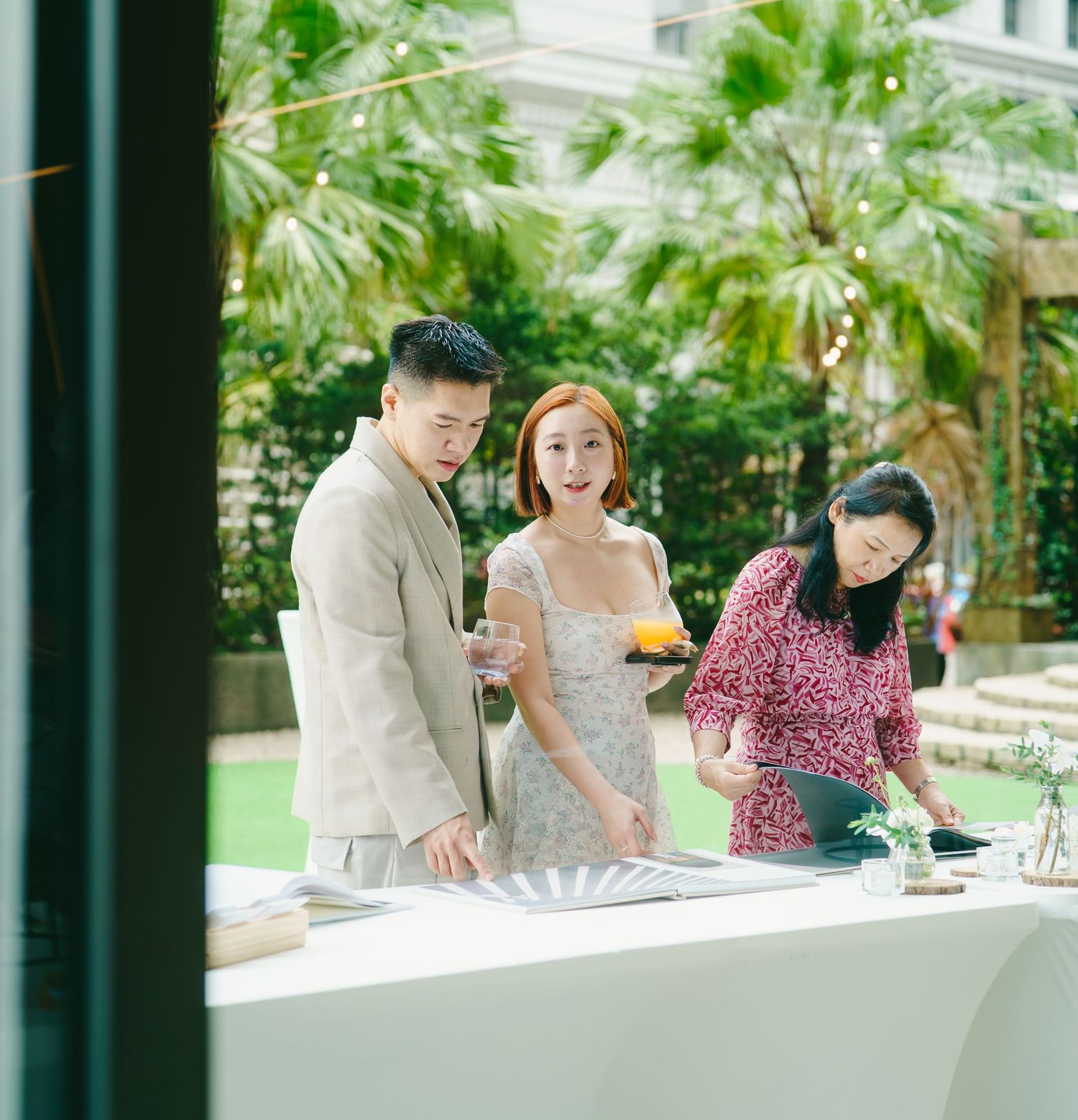 Group enjoying drinks and socializing at an upscale venue with lush greenery in the background.