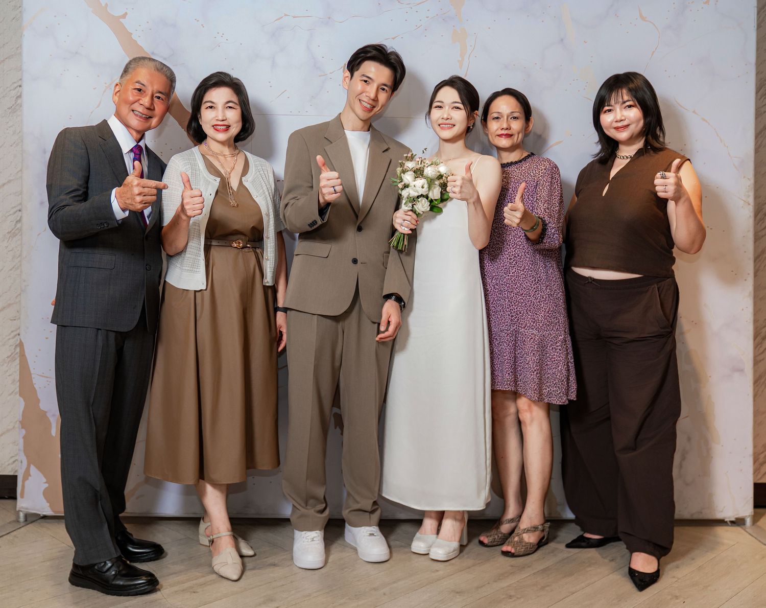 Wedding party members' feet and shoes lined up against a light colored wall showing diverse formal footwear styles.