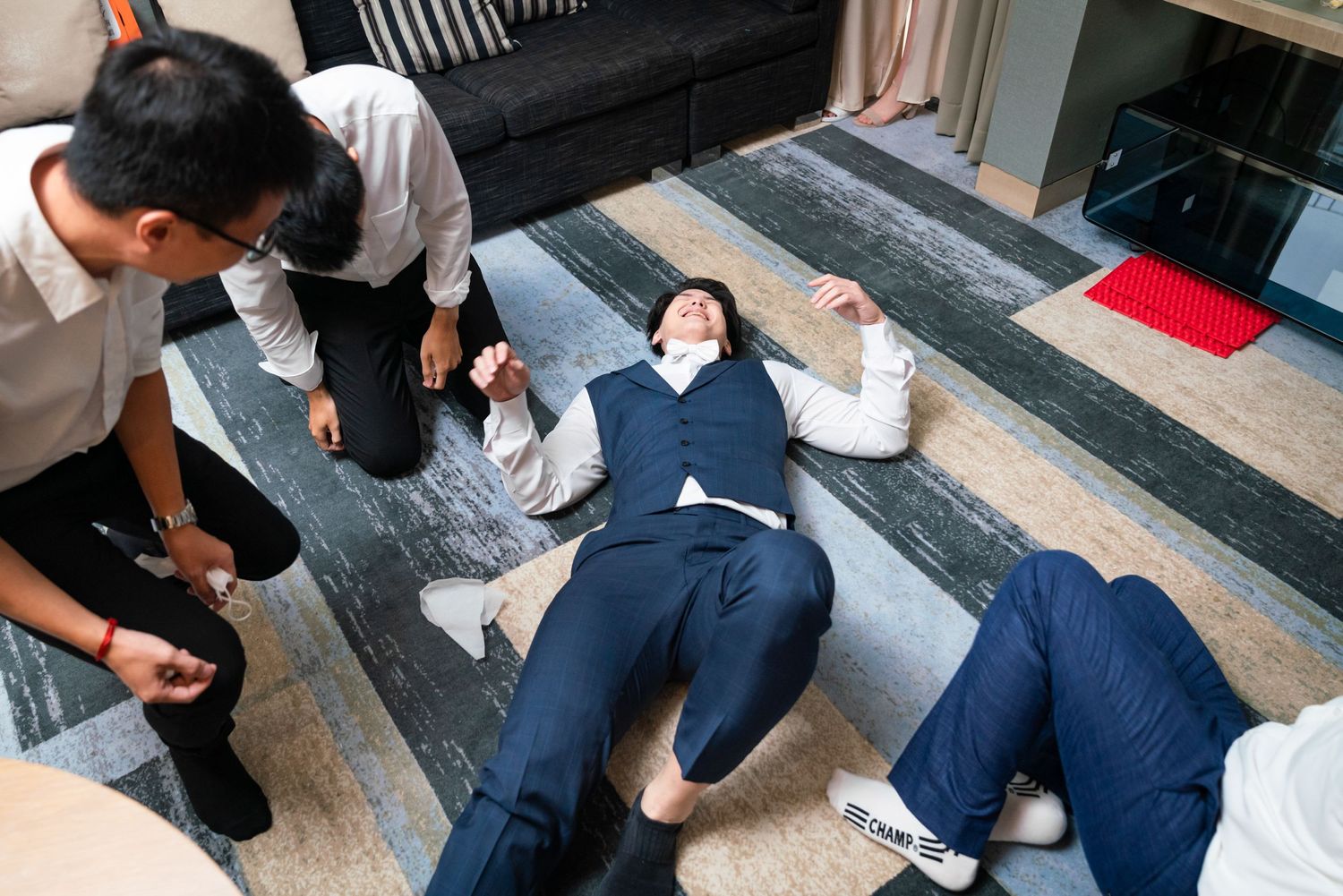 Business professionals in suits lying on floor during teambuilding exercise at office.