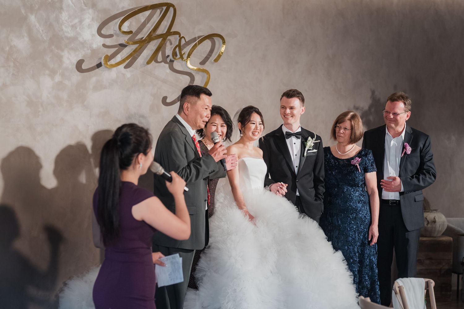 Wedding guests dance and celebrate during an indoor reception with bokeh lights in the background.