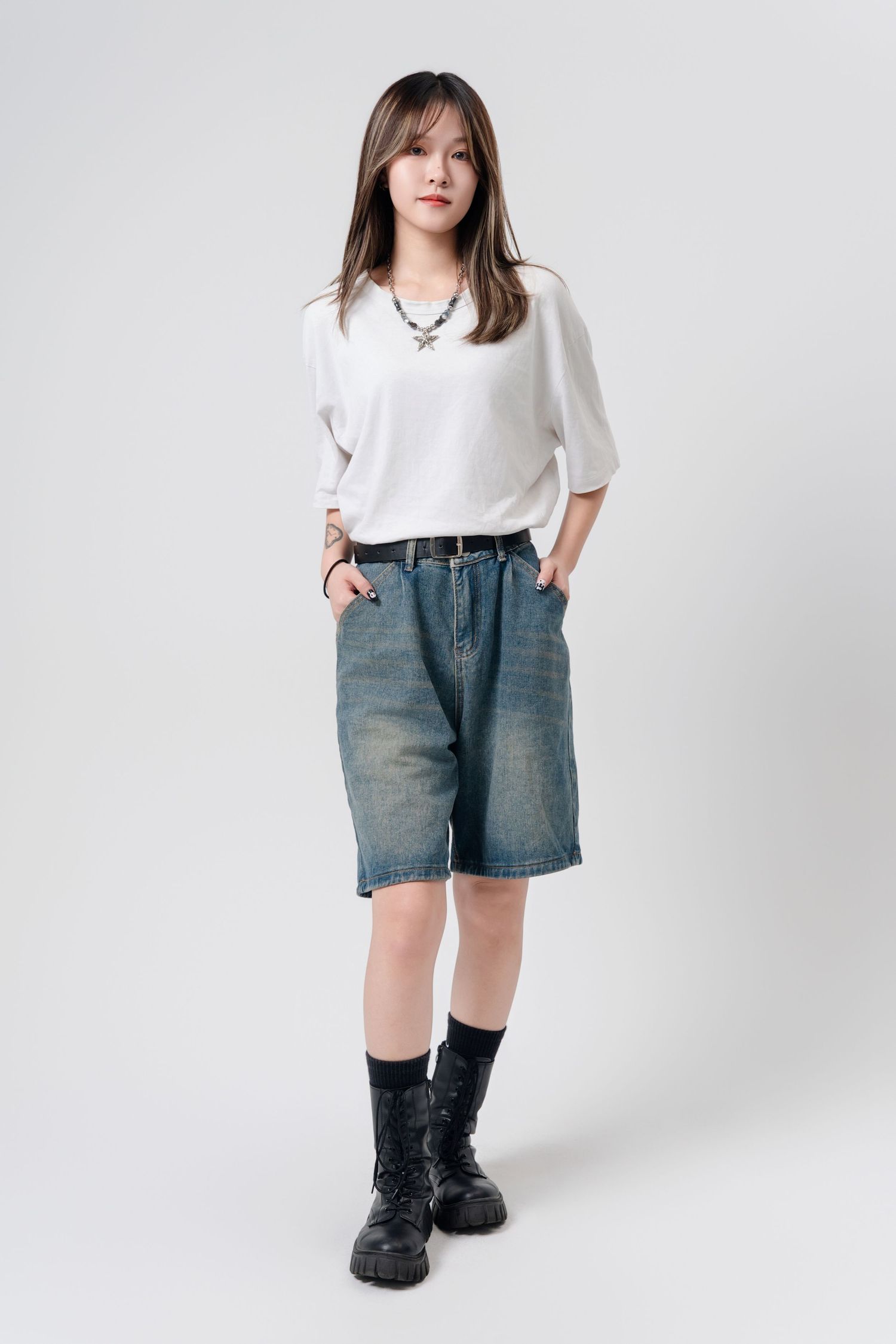 Model wearing a white t-shirt, denim shorts and black boots poses against white background in three different angles.