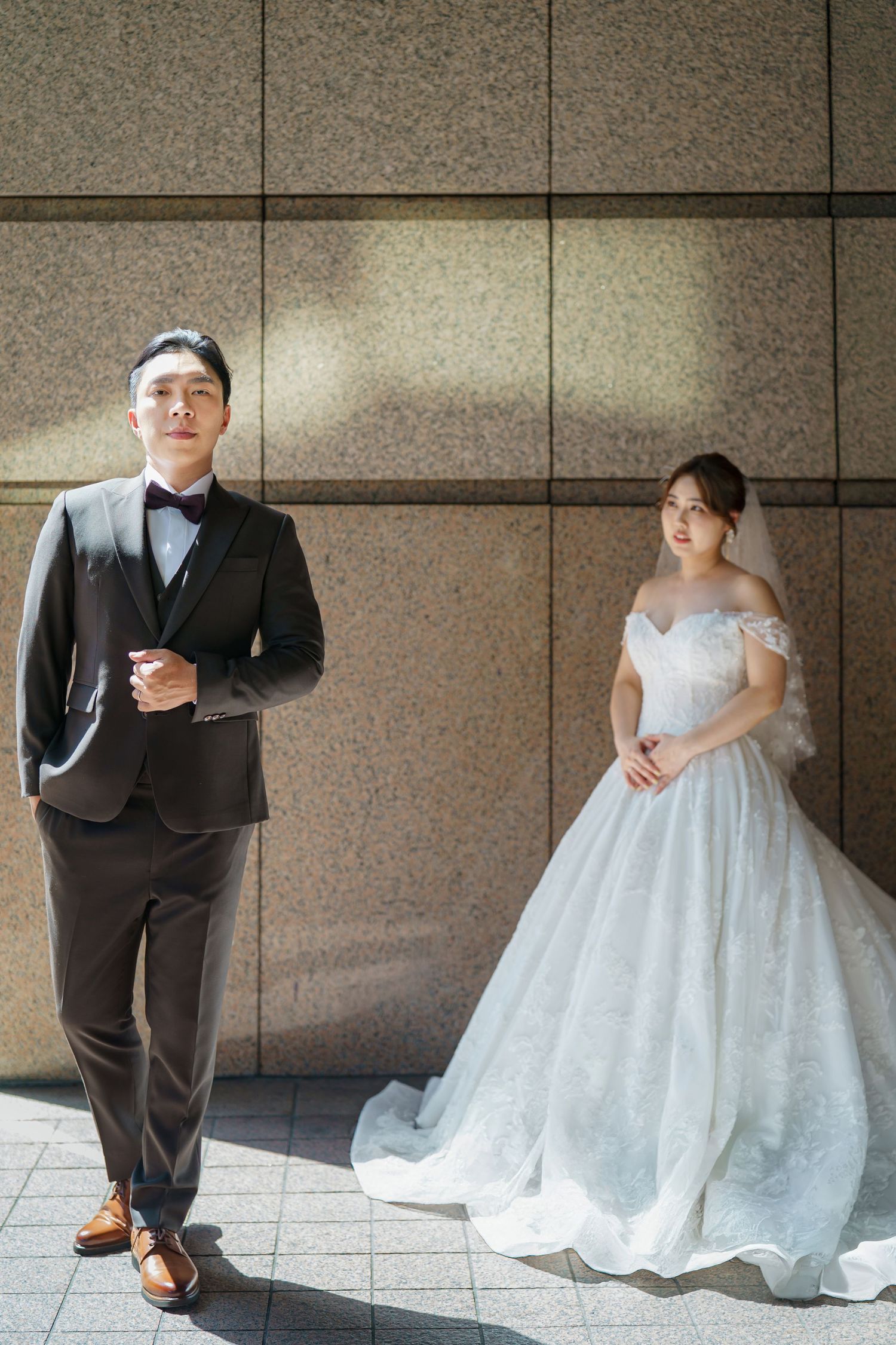 A couple in wedding attire poses creatively in a series of artistic shots against a modern architectural wall.