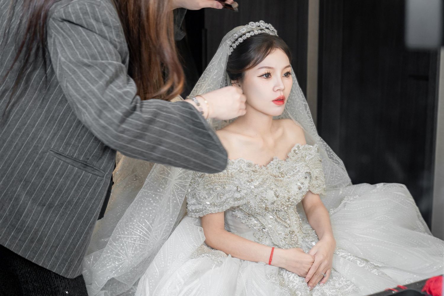 A bride in an elegant silver-gray tulle gown with embellished details poses in a romantic indoor setting.