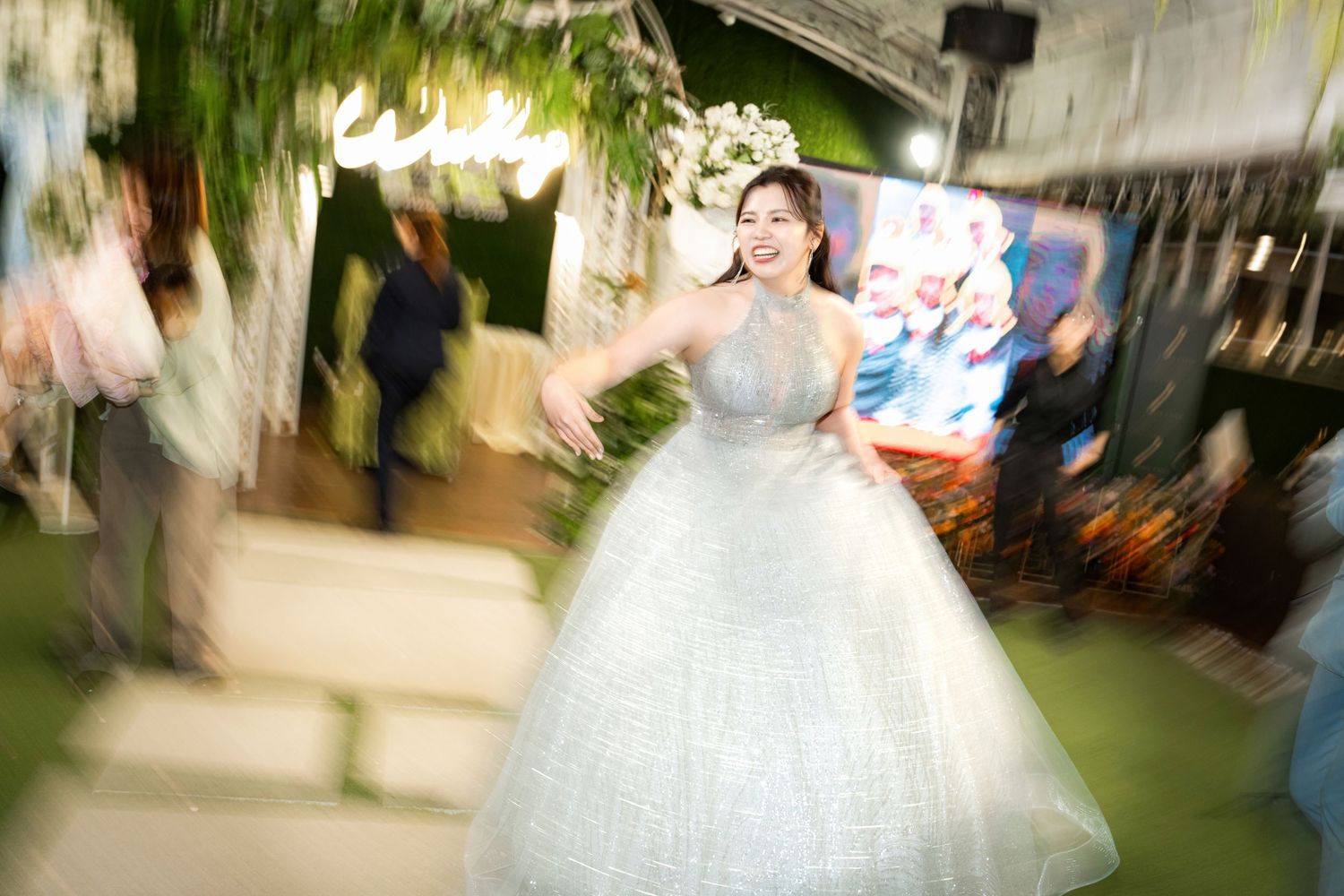 A wedding ceremony procession with a bride in a white gown walking down an aisle lined with guests.