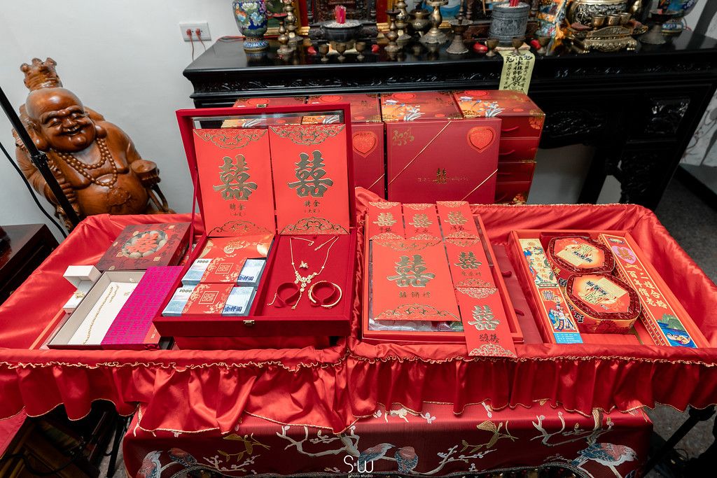 Traditional Chinese wedding gifts and red envelopes displayed on red cloth.
