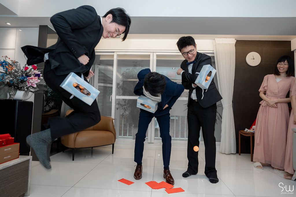 Groomsmen in suits playfully jumping and posing during pre-wedding preparations.