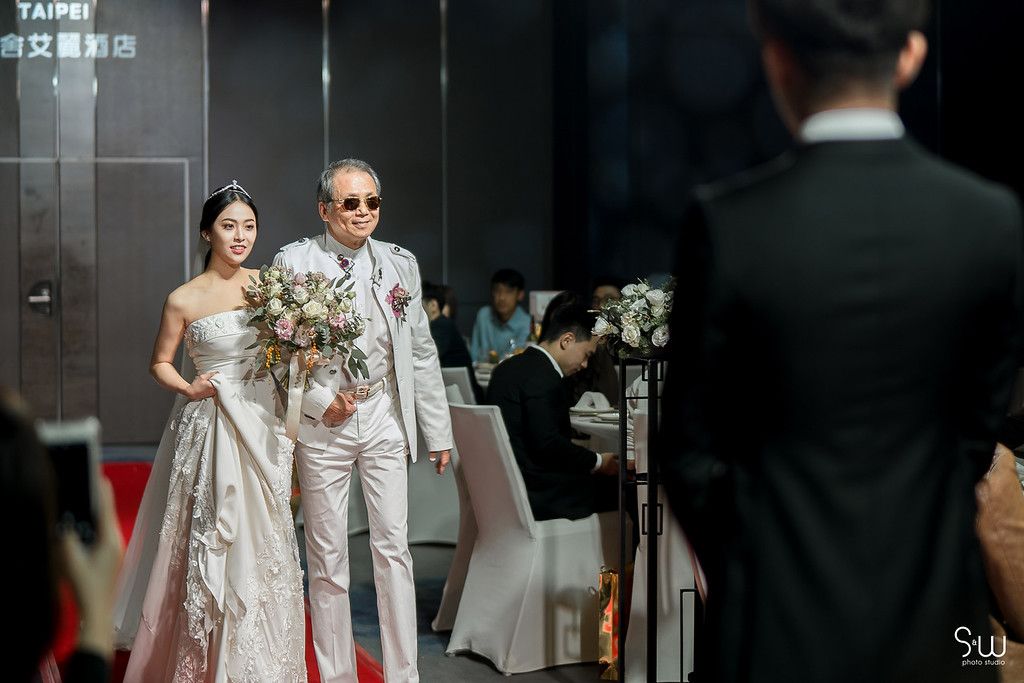Wedding couple makes grand entrance in elegant venue with white and black decor.