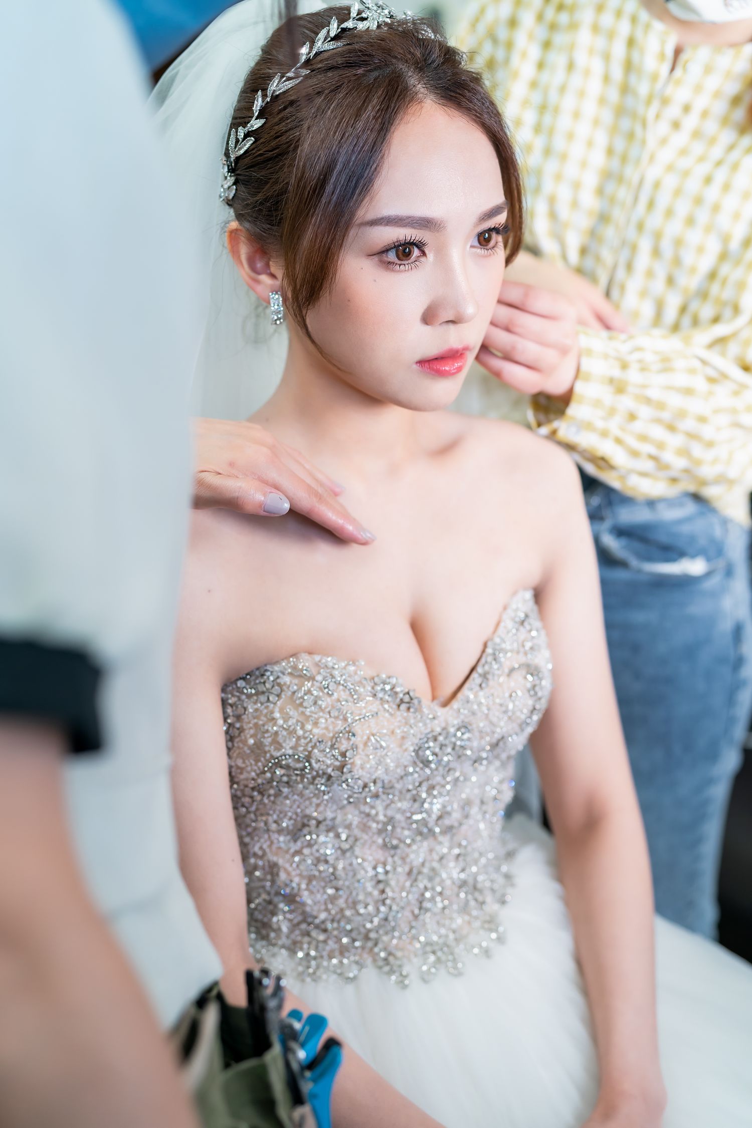 Side profile of bride in beaded wedding dress during preparation.