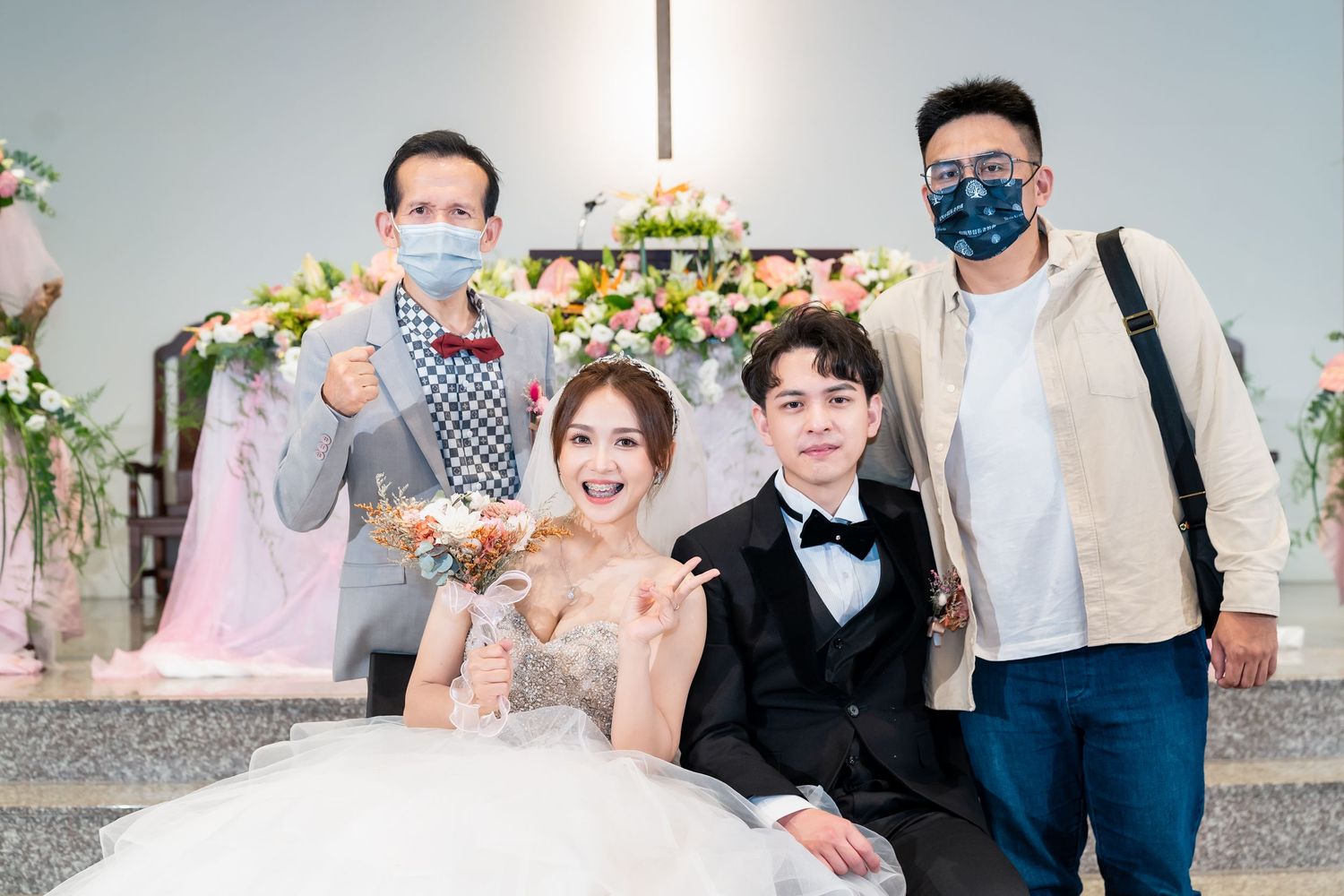 Wedding photo with couple and guests wearing masks during celebration.