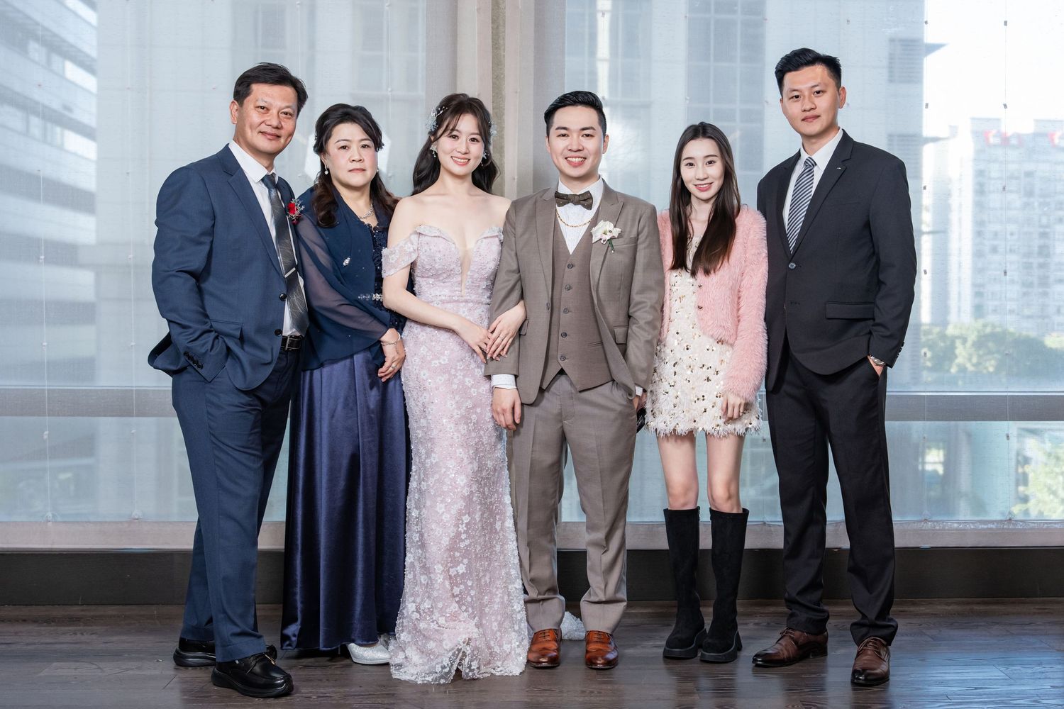 A group of people in formal attire pose together in front of a city skyline view.