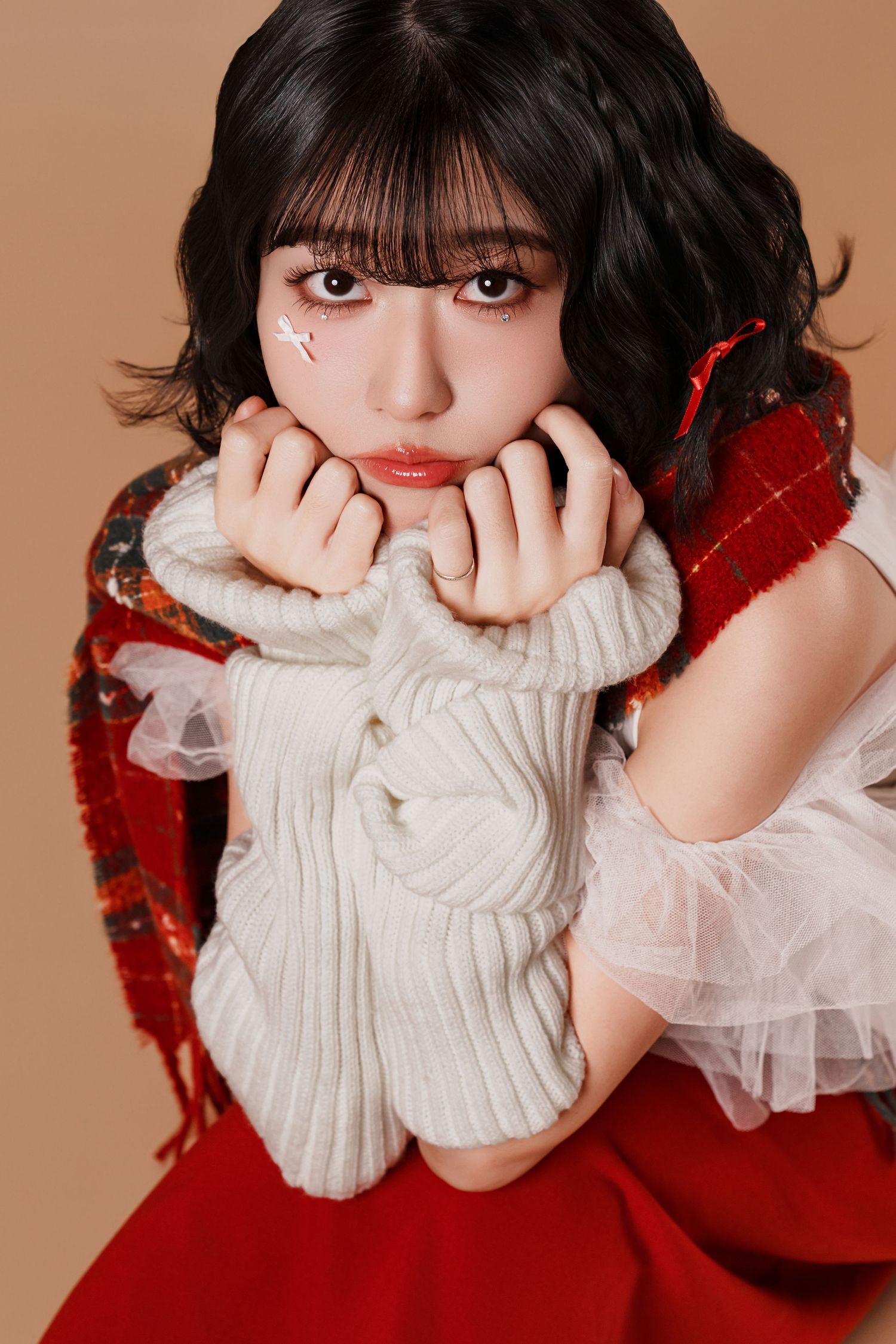 A series of close-up portraits showing someone wearing a white turtleneck sweater and red accessories against a beige backdrop.