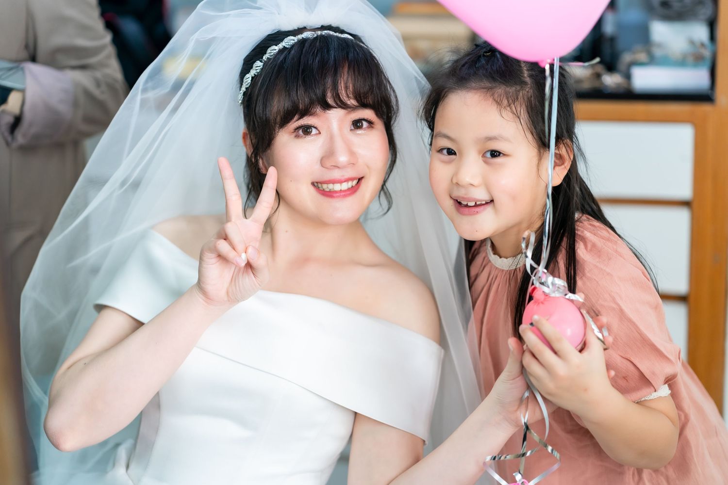 A joyful wedding moment with a bride and young guest holding a pink balloon.
