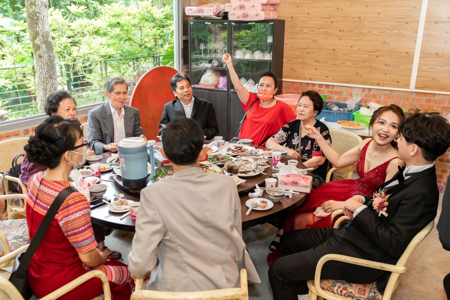 Group gathering around table for casual outdoor meal on wooden deck.