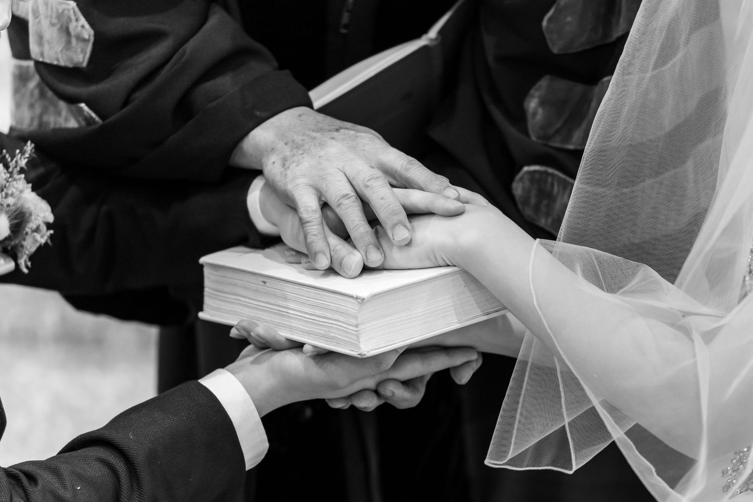 Hands placed on a bible during a traditional wedding ceremony exchange of vows.