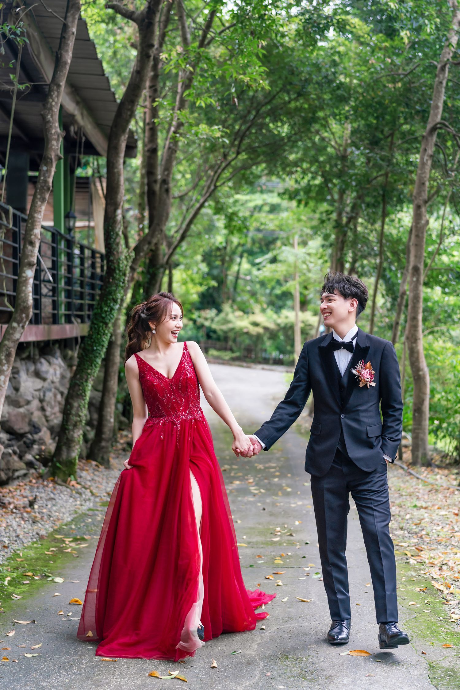 Romantic walk in formal attire along tree-lined pathway.