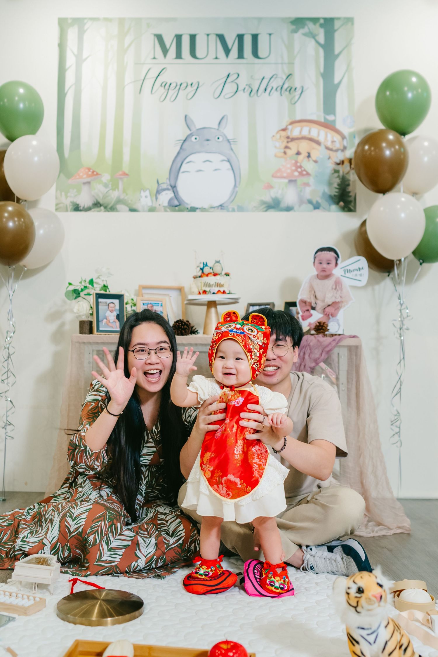 Family celebrates a festive birthday party with green and white balloons and decorations in an elegantly styled room.