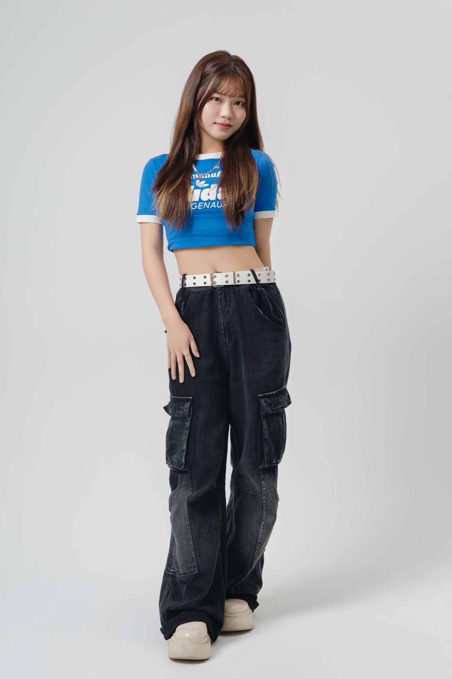 A series of four fashion photos showing someone wearing a blue t-shirt and black cargo overalls against a white backdrop.