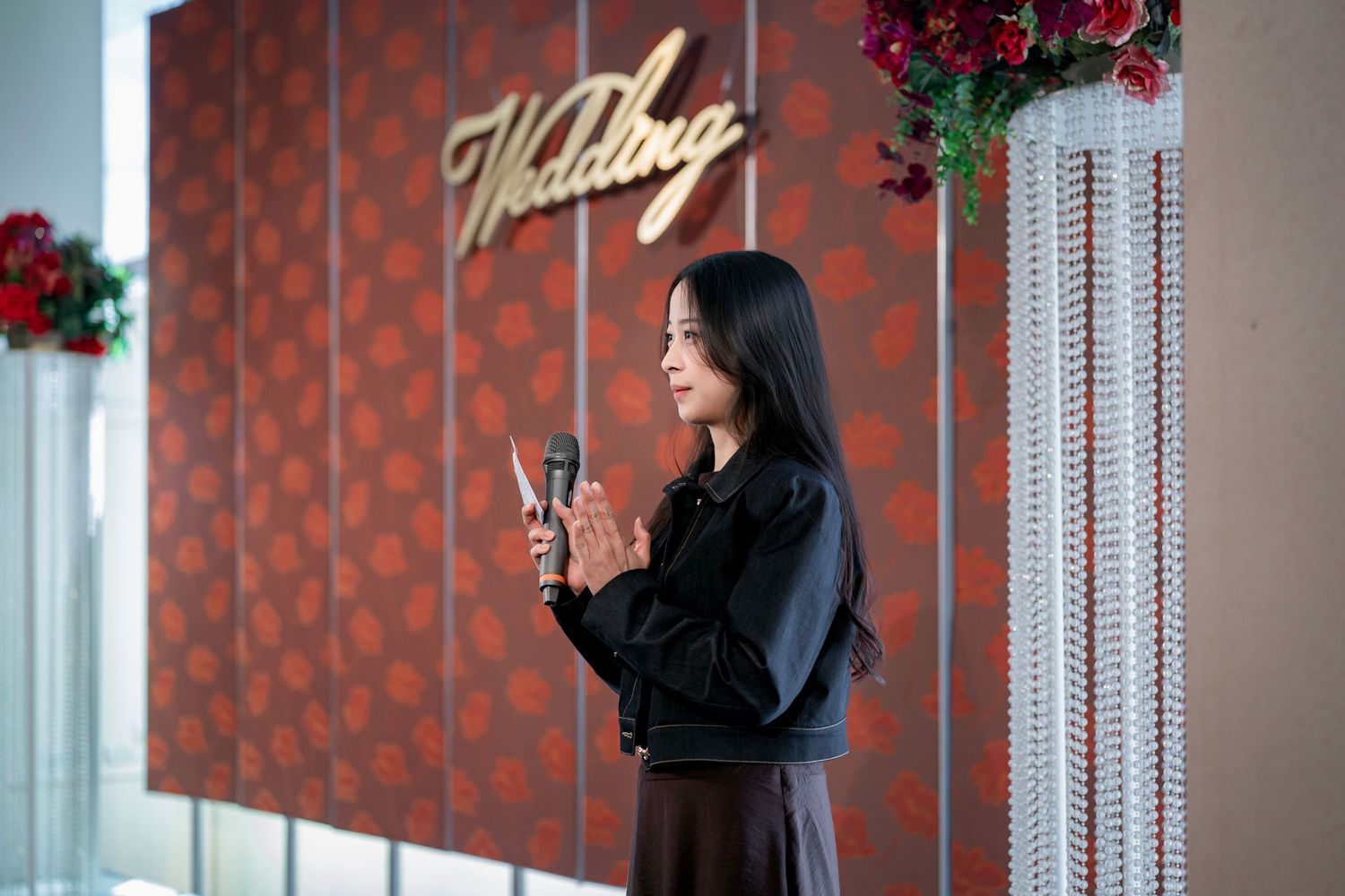 A woman in a black hijab poses against a red polka dot wall in a modern interior setting.