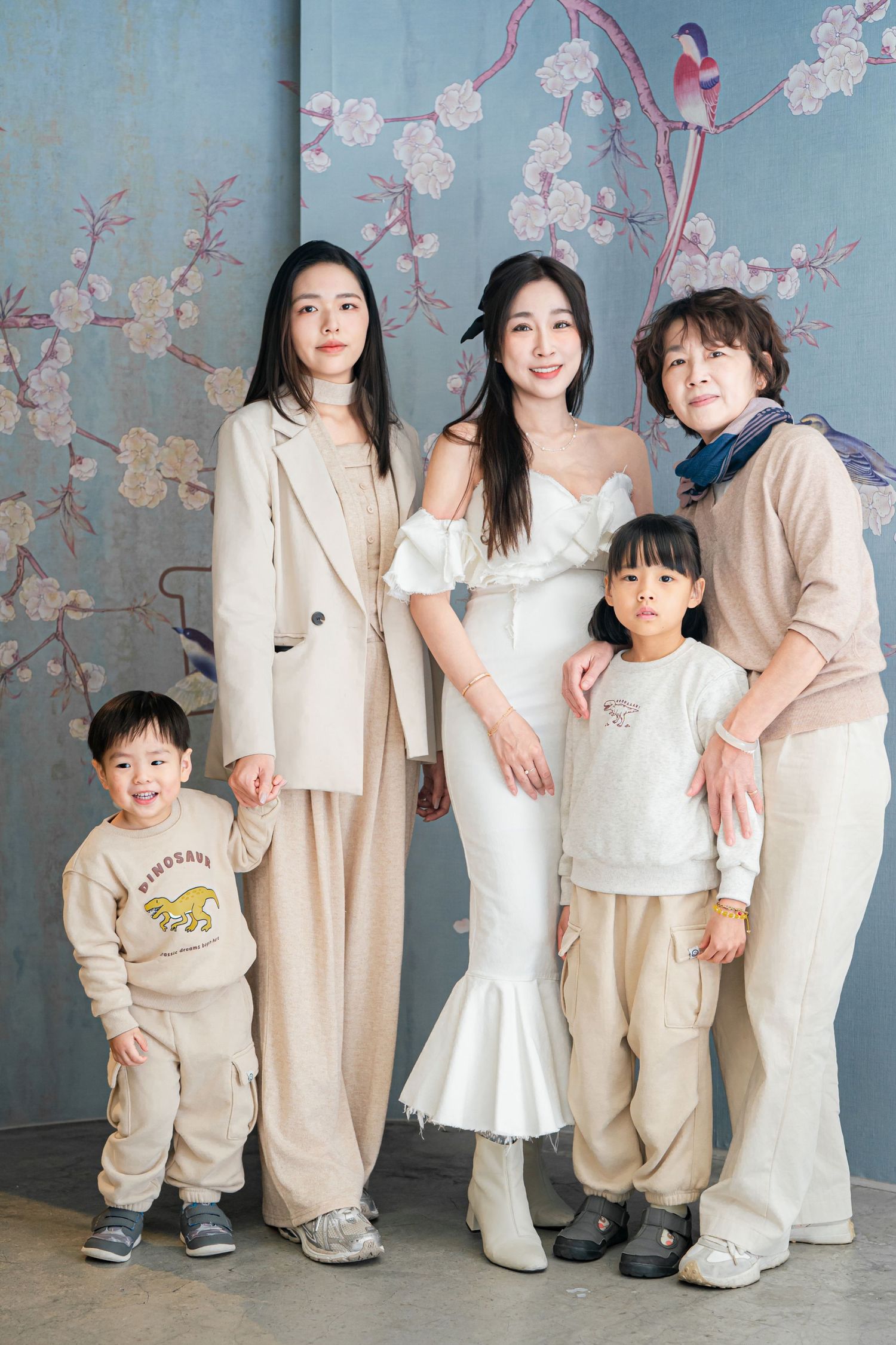 A series of family portraits showing people in coordinated cream and white outfits posing against a floral backdrop.