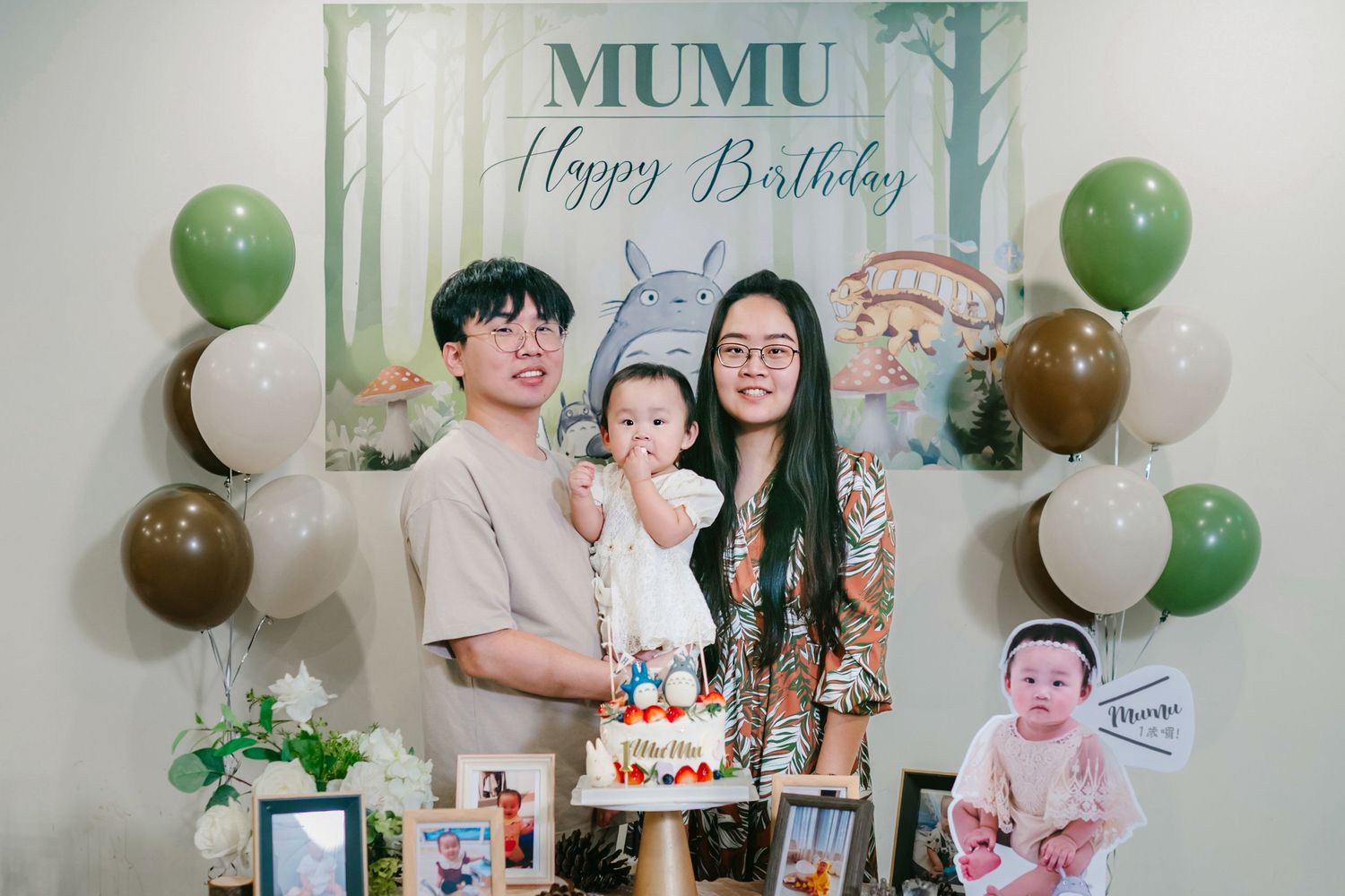 Birthday party decorations in green and white with a cake, balloons, and a MuMu theme for a first birthday celebration.