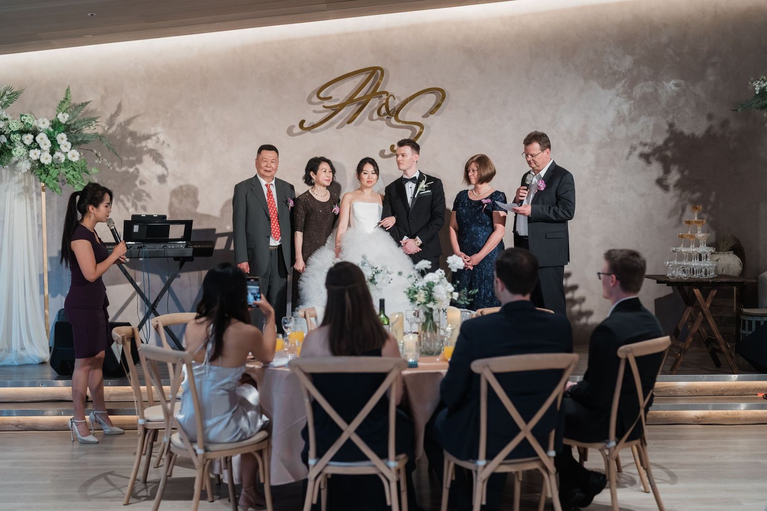 Wedding guests seated at a farmhouse table enjoy a casual reception dinner at an industrial-style venue.