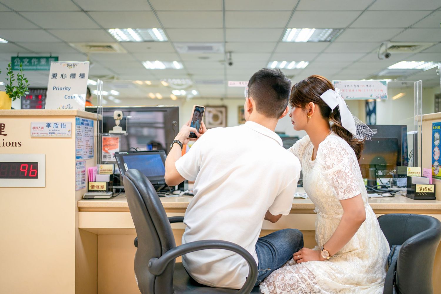Medical staff in white coats work at a busy hospital counter with computers and medical equipment.