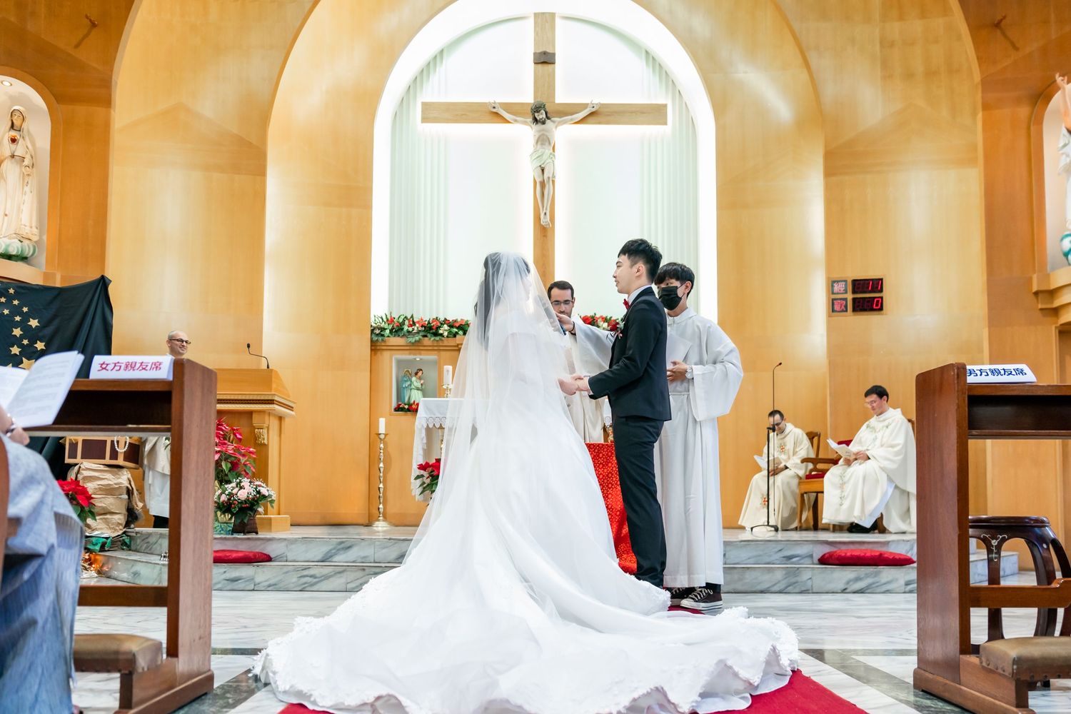 Traditional church wedding ceremony with a long white train dress beneath an arched altar and crucifix.