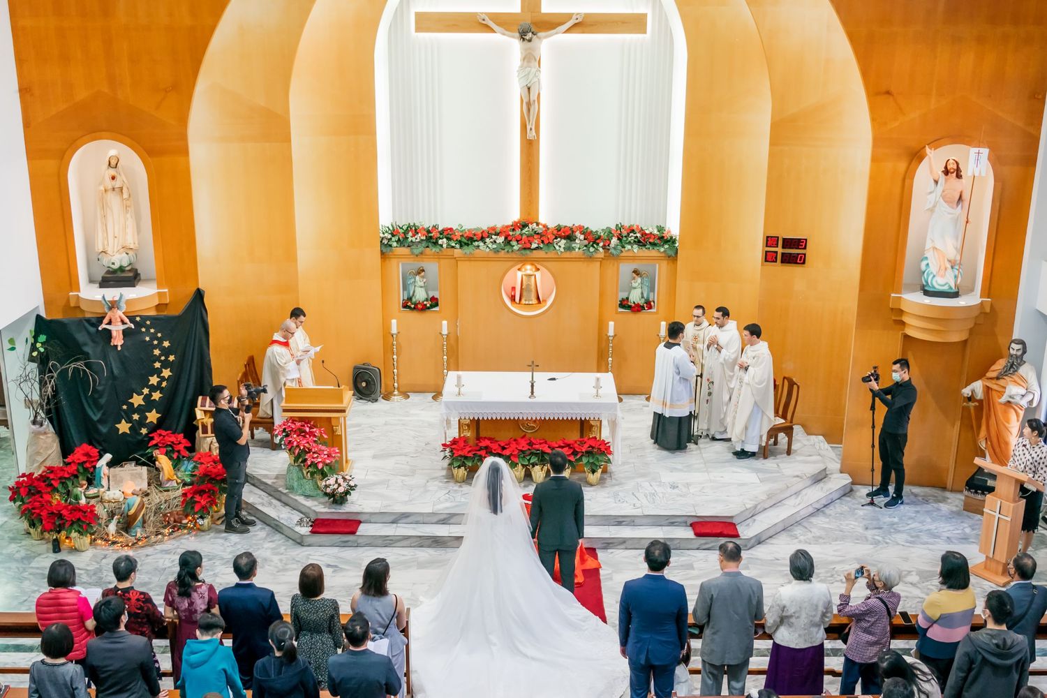 Catholic wedding ceremony in progress with decorated altar and attendees gathered in church pews.