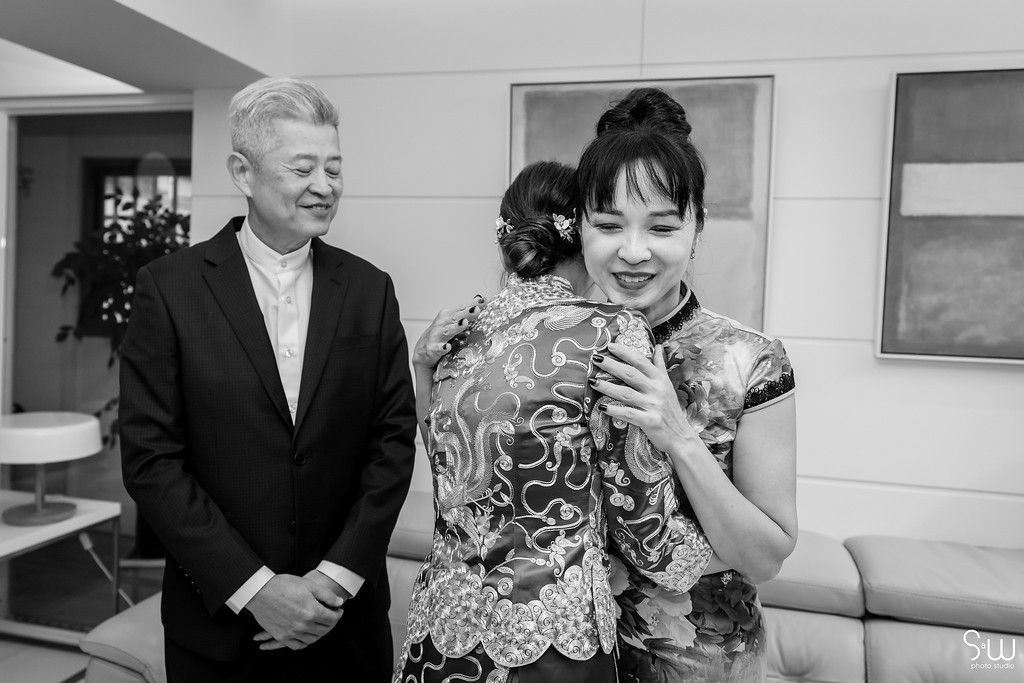 A black and white photo showing a traditional Chinese qipao dress being admired during a formal occasion.