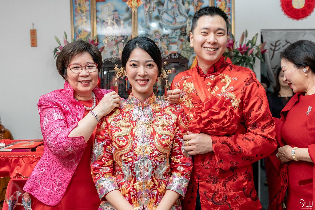 Wedding celebration with traditional Chinese decor and red formal wear.