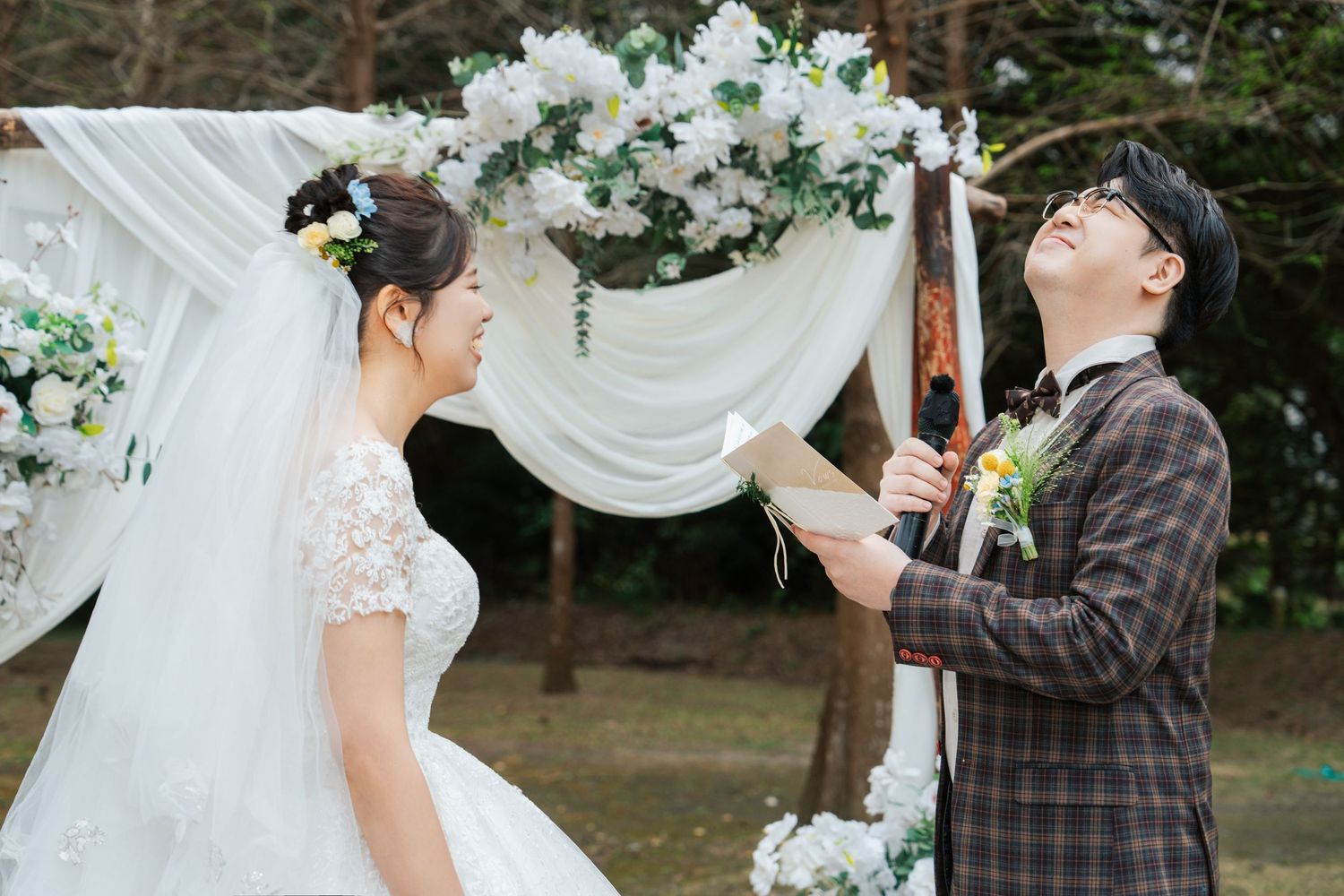 A couple shares an intimate moment under a floral arch during their outdoor wedding ceremony.