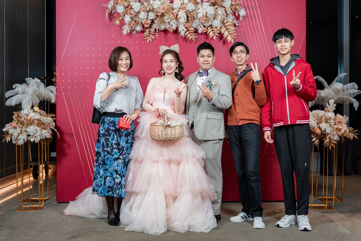 Celebration photos showing multiple group poses against a pink wall with elegant white flower decor.