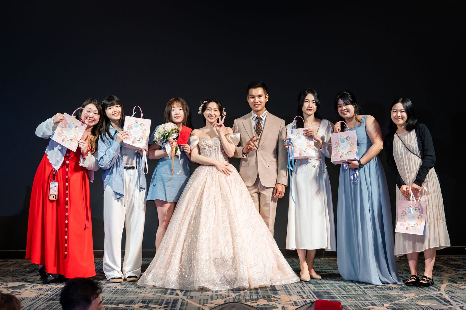 Bride and groom pose with bridesmaids in elegant dresses at a wedding reception celebration.