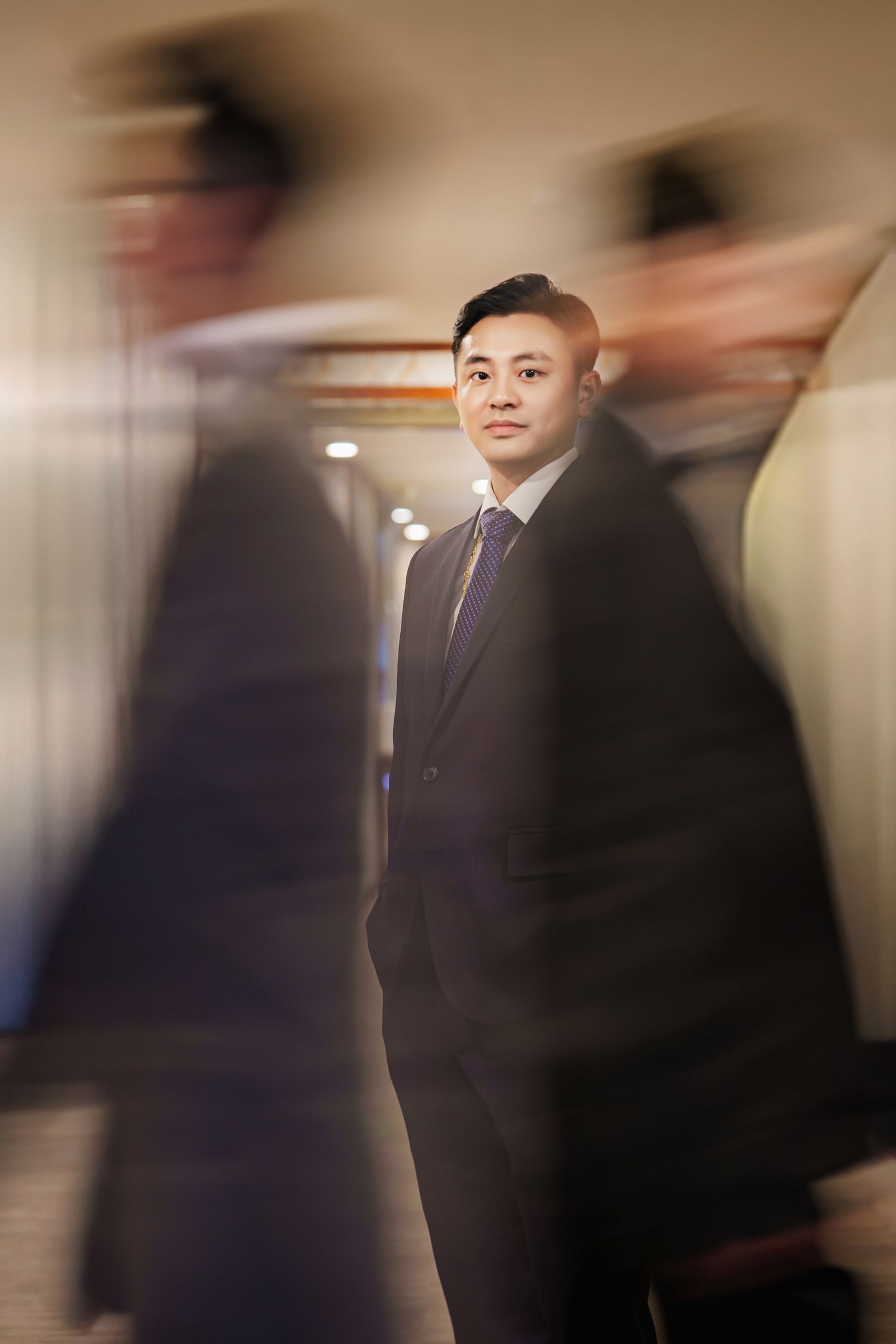 Motion blur photograph shows a person in a dark business suit walking through an indoor space with beige walls.