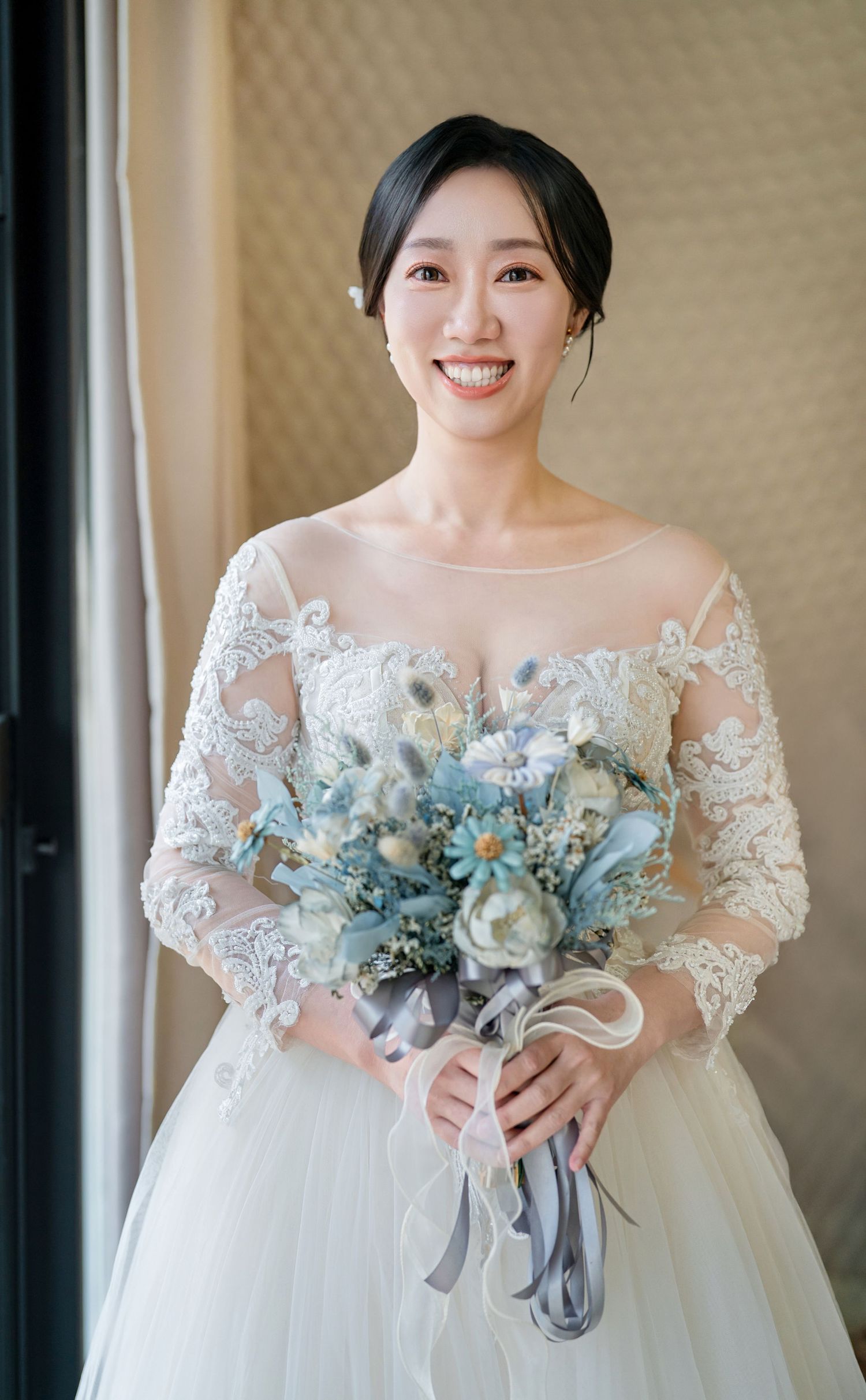 Beautiful bridal portraits showing white lace wedding dress and elegant blue and white floral bouquet with ribbon accents.