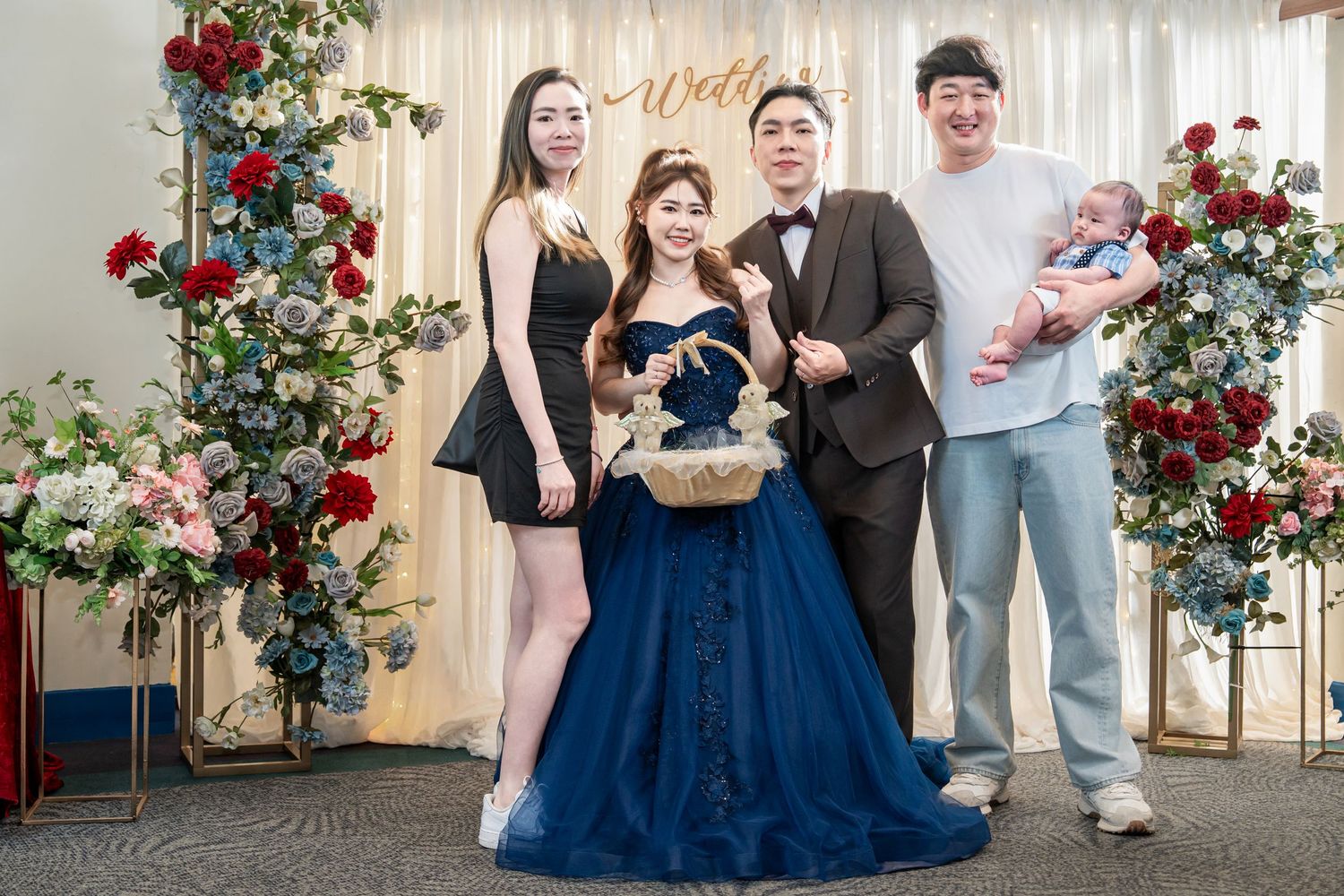 Elegant group photo with floral decorations featuring a navy blue gown and formal attire against a light backdrop.