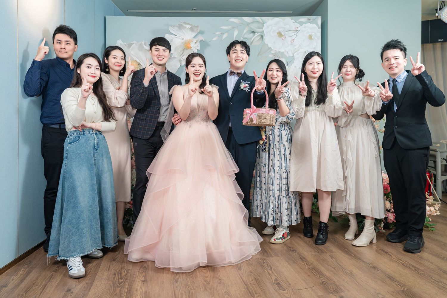 Wedding guests in formal attire gather for group photos in an elegant indoor venue.