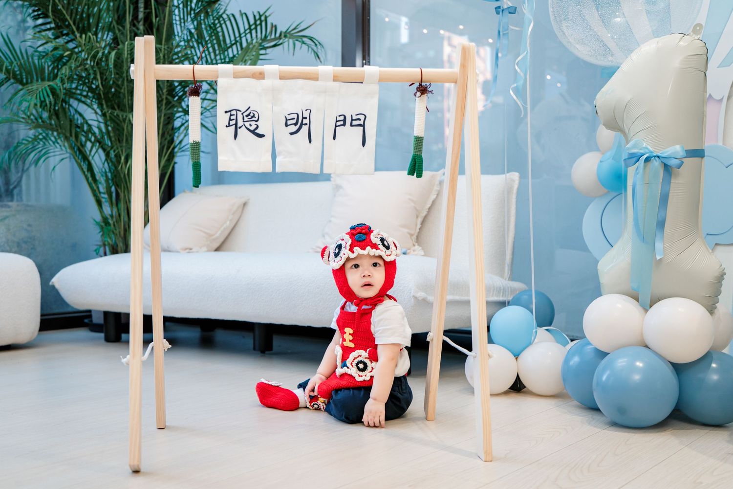 A modern pastel-colored playroom interior with wooden furniture, blue balloons, and soft white decorative elements.