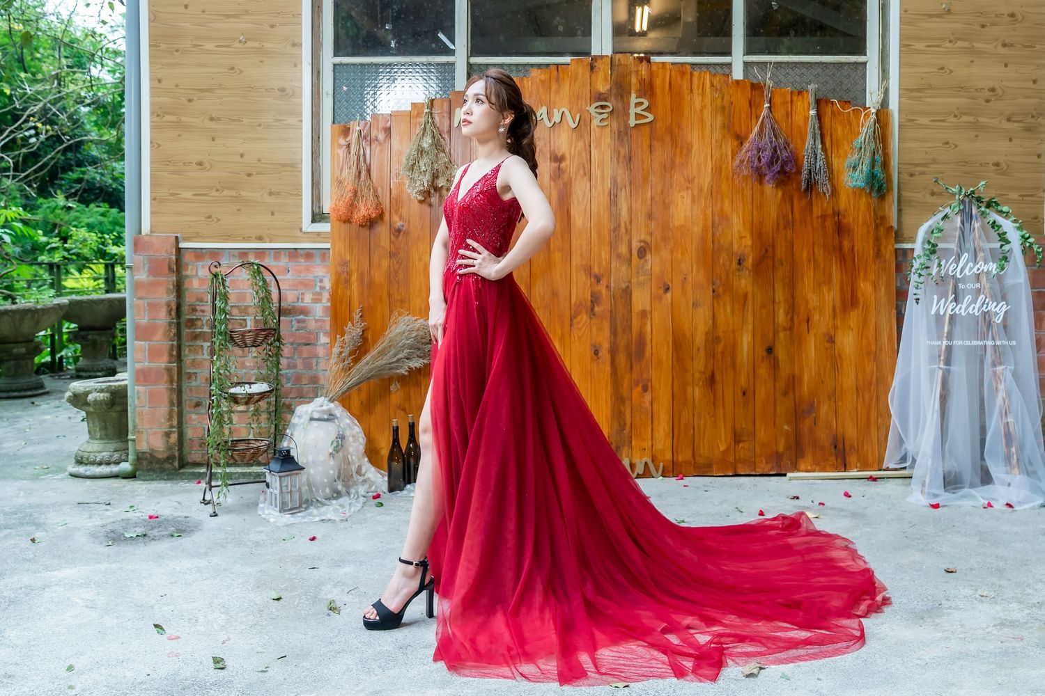 Beautiful red evening gown with long train photographed against rustic wooden backdrop.