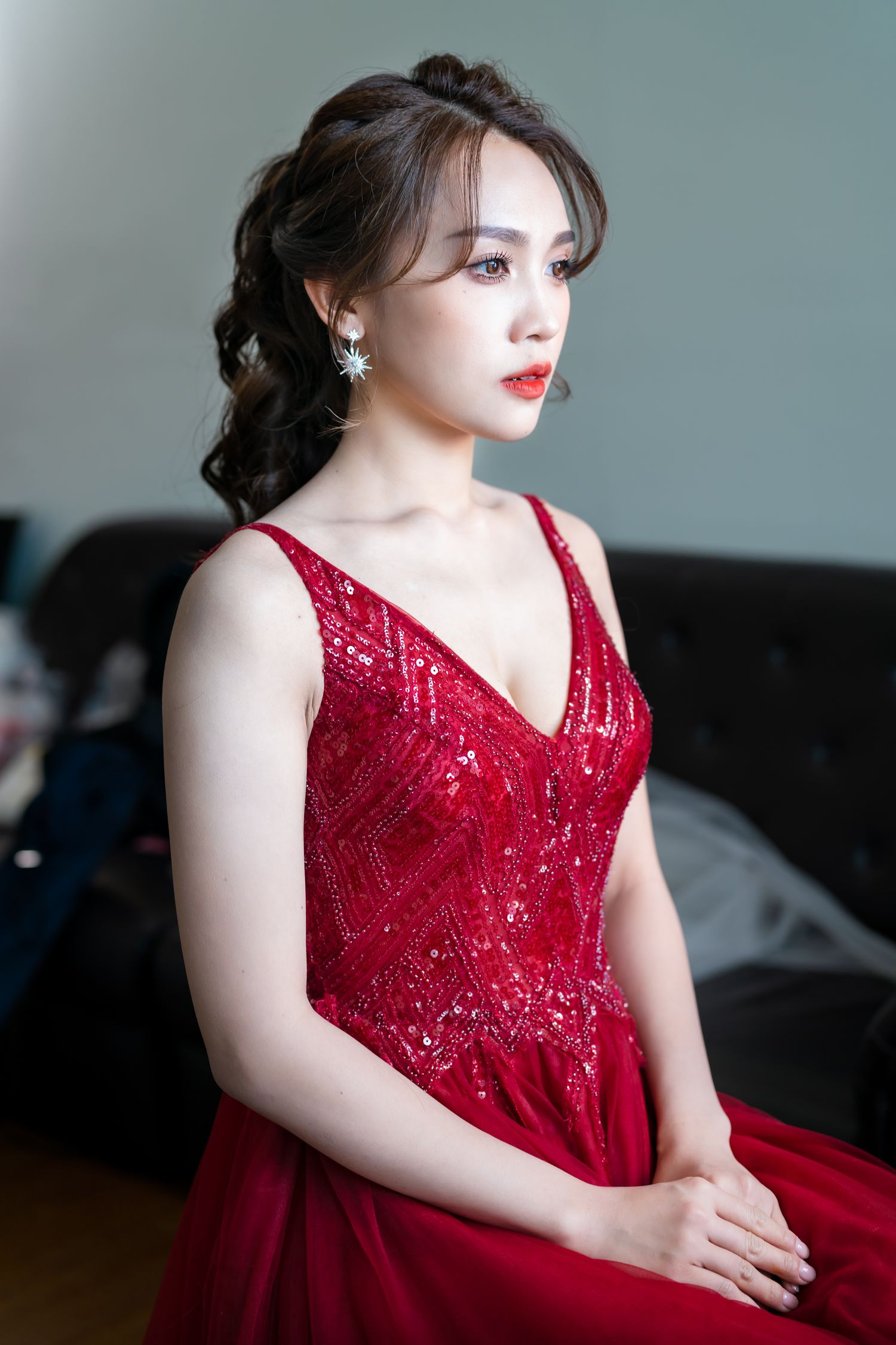 Elegant woman in red lace gown poses during formal event.