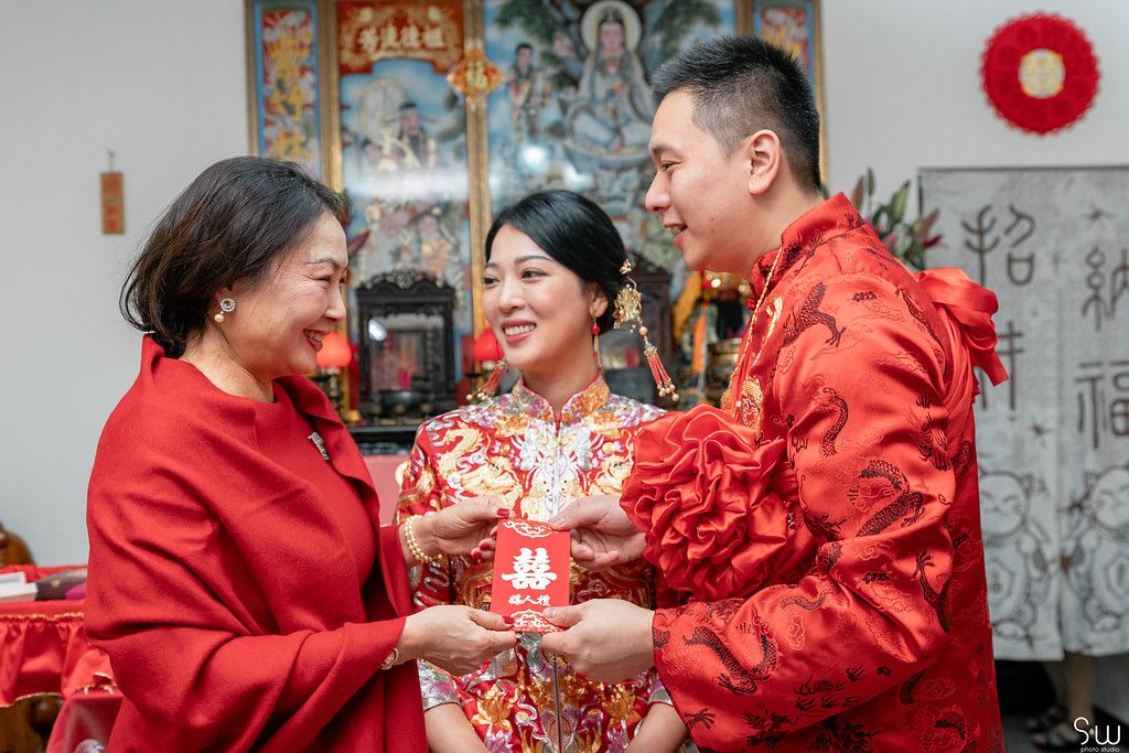 Tea ceremony celebration with family members in traditional Chinese wedding attire.