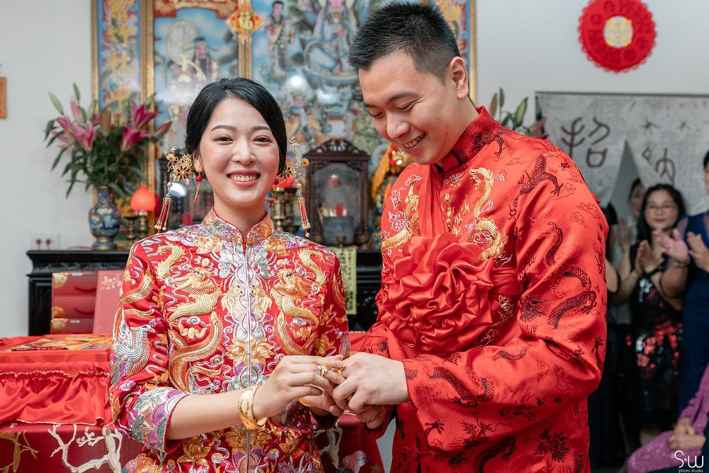 Traditional Chinese wedding ceremony with couple in matching red attire.