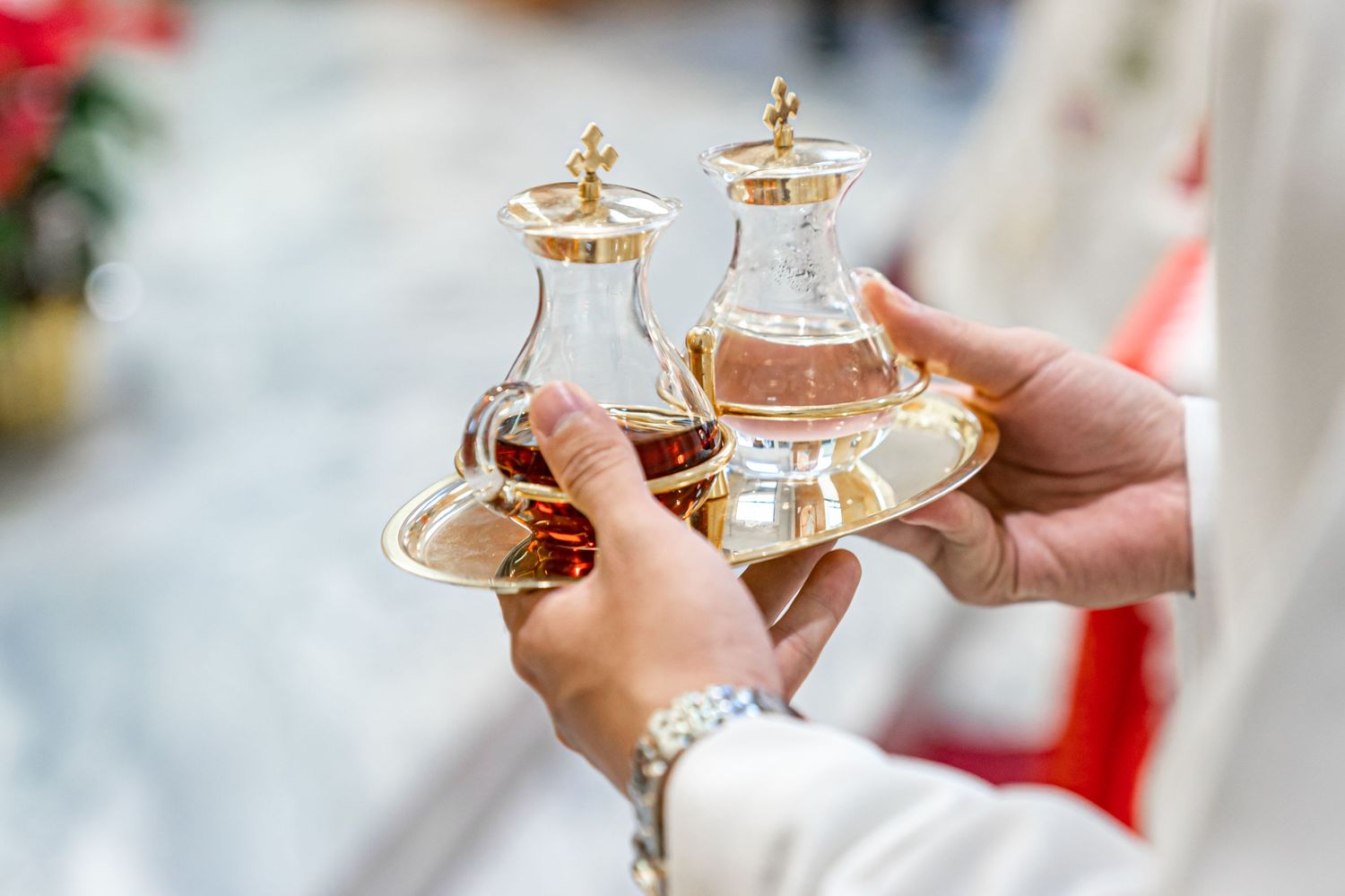 Close-up of hands holding ceremonial glass vessels during a religious ceremony.