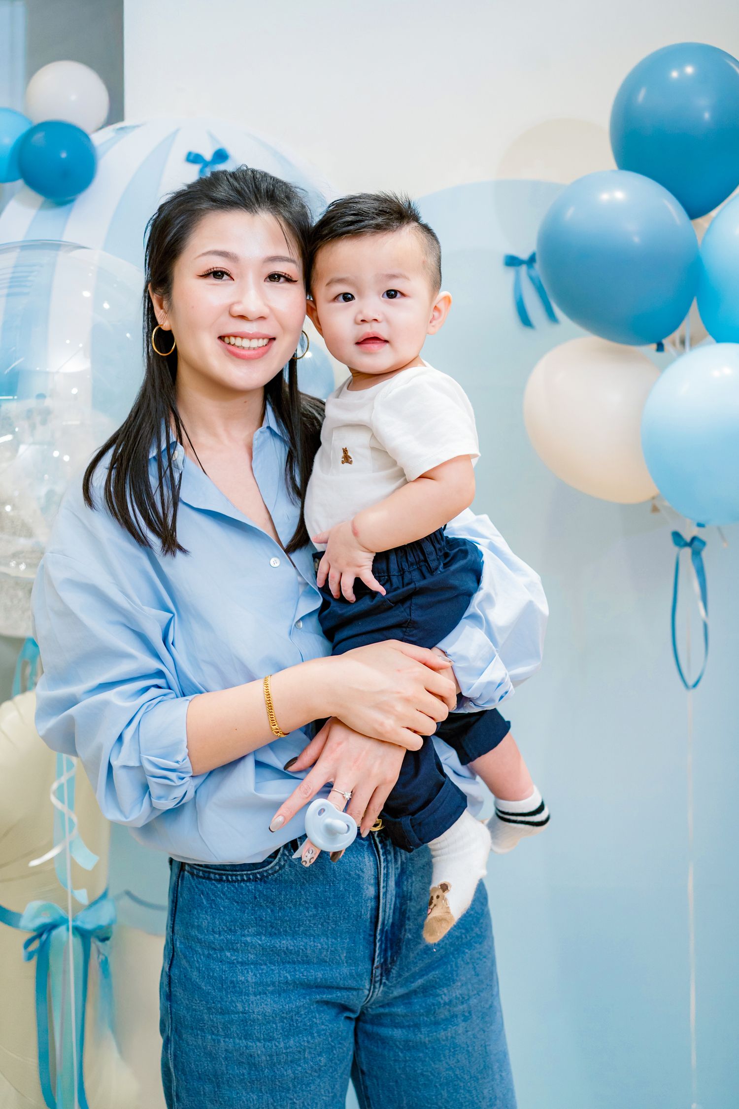 A series of blue and white balloon decorations create a festive backdrop for a family photo session.