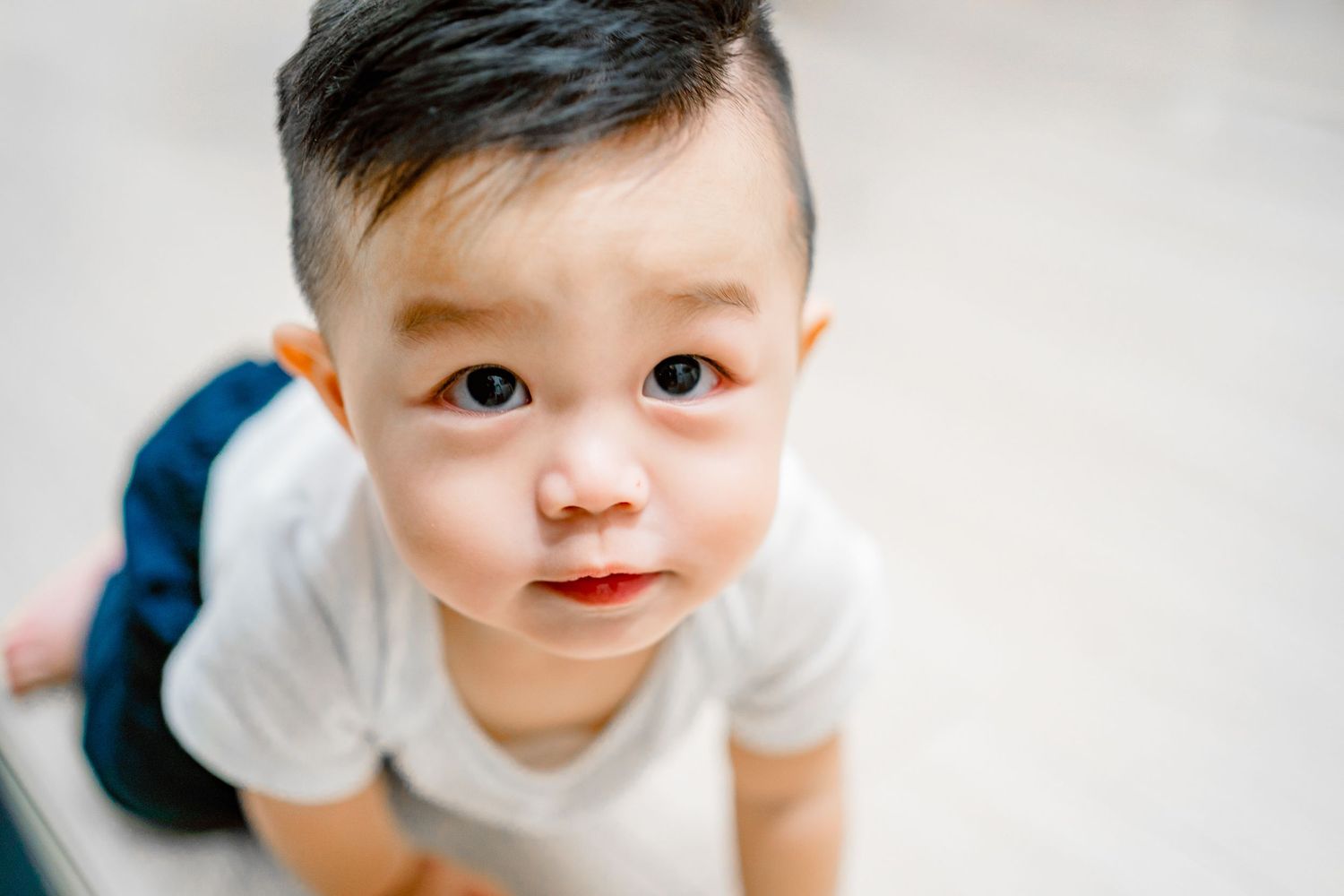 Close-up photo series of a baby in white clothing showing different expressions and angles.