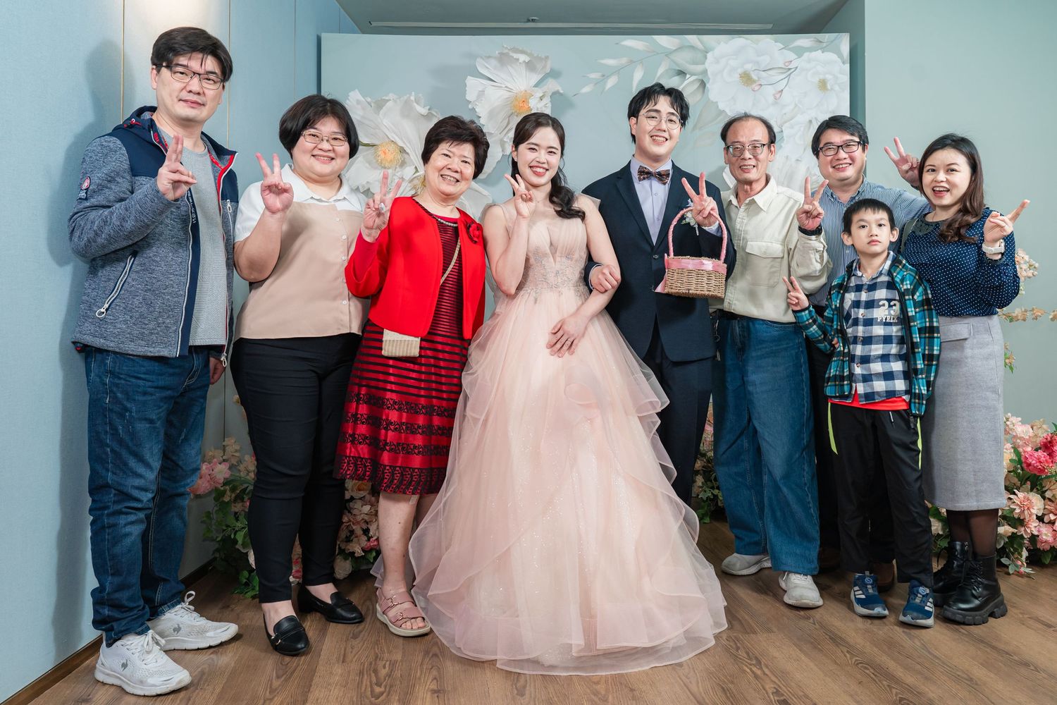 A group of people pose together at a formal celebration with someone wearing a pink ballgown in the center.