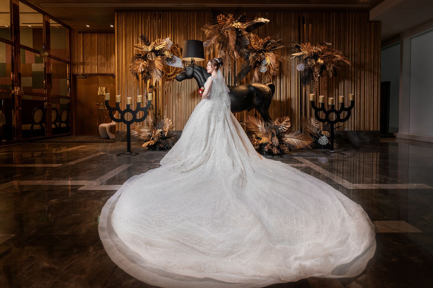 Elegant wedding dress with dramatic cathedral-length train against romantic floral backdrop in dimly lit venue.