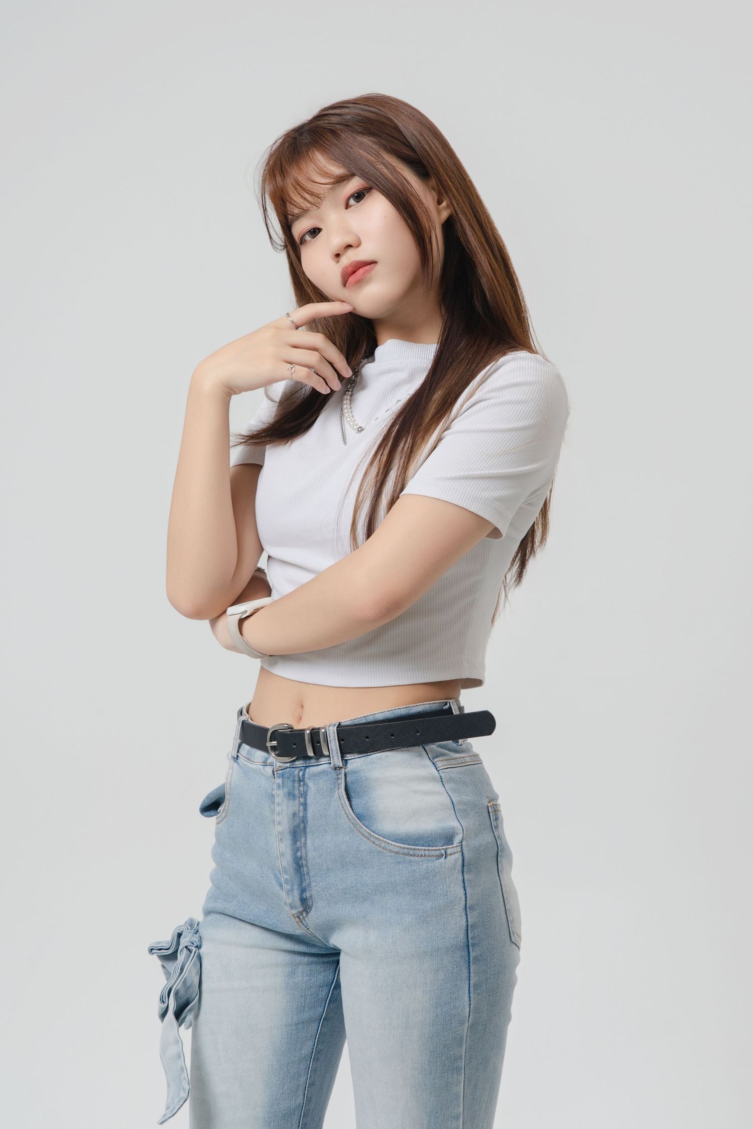 Fashion model in white crop top and light wash jeans poses against white background in multiple dynamic poses.
