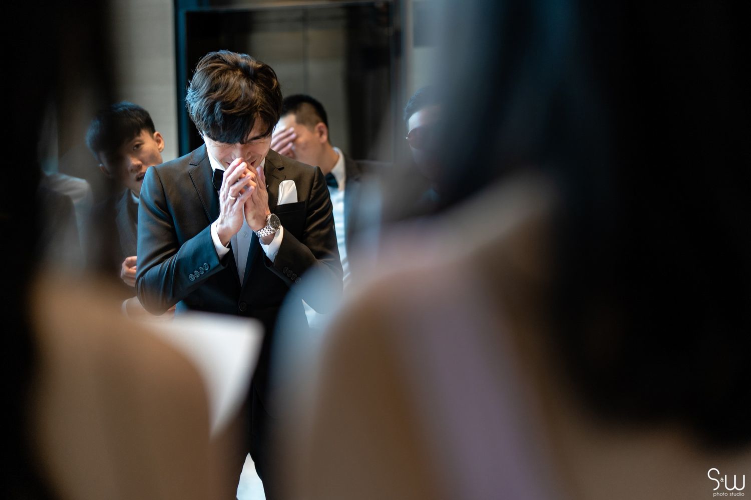 An emotional moment captured during a wedding ceremony in dark, intimate lighting.